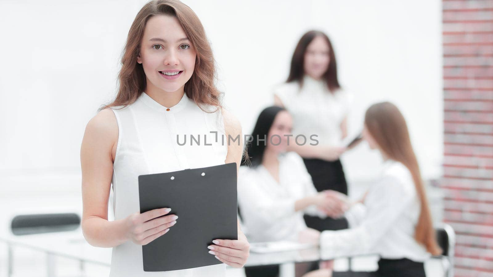 confident young business woman with clipboard on the background of business team.