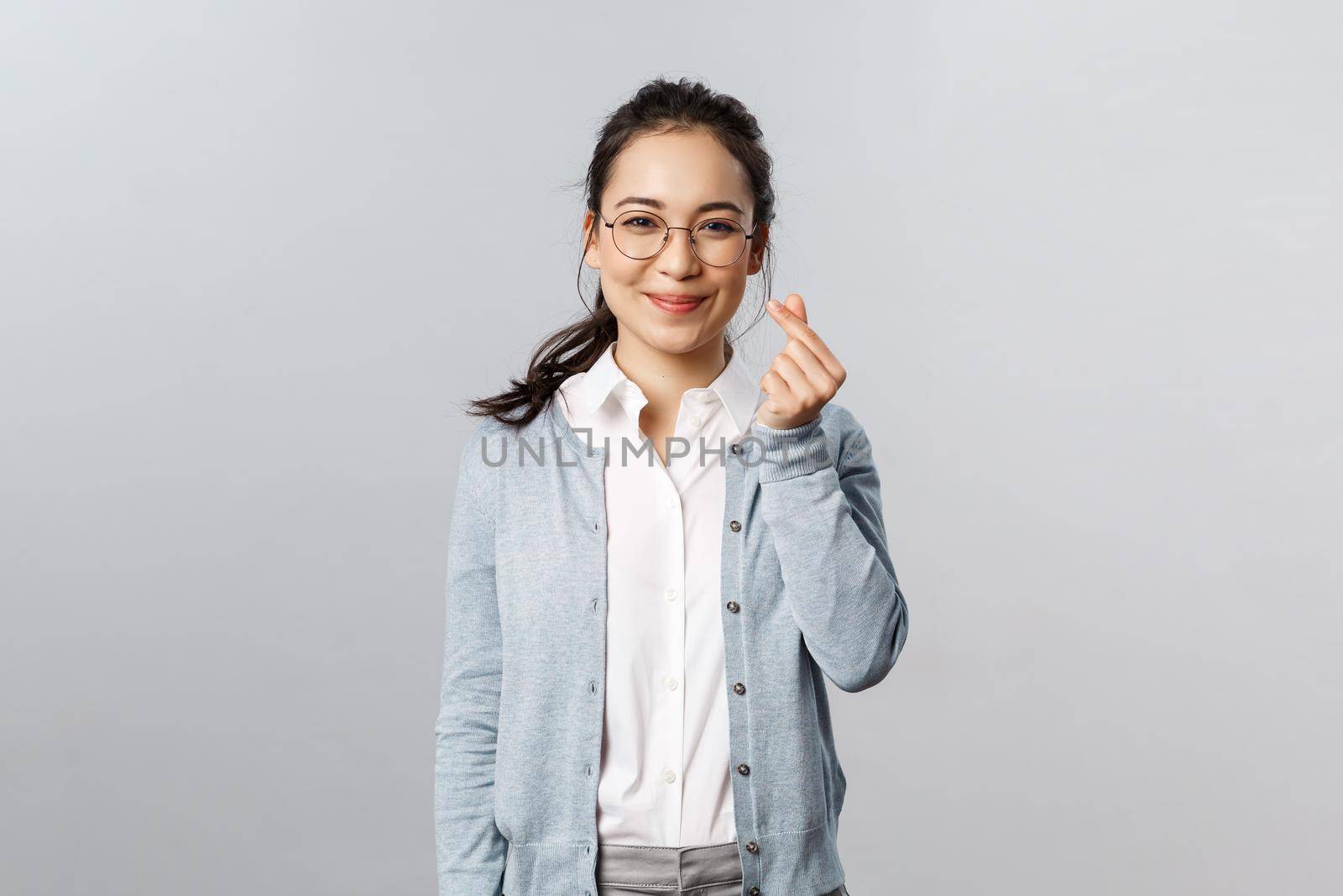 Emotions, people and lifestyle concept. Optimisic cute asian woman, young tutor in glasses entertain small kids during classes online education school, show korean heart sign and smile.