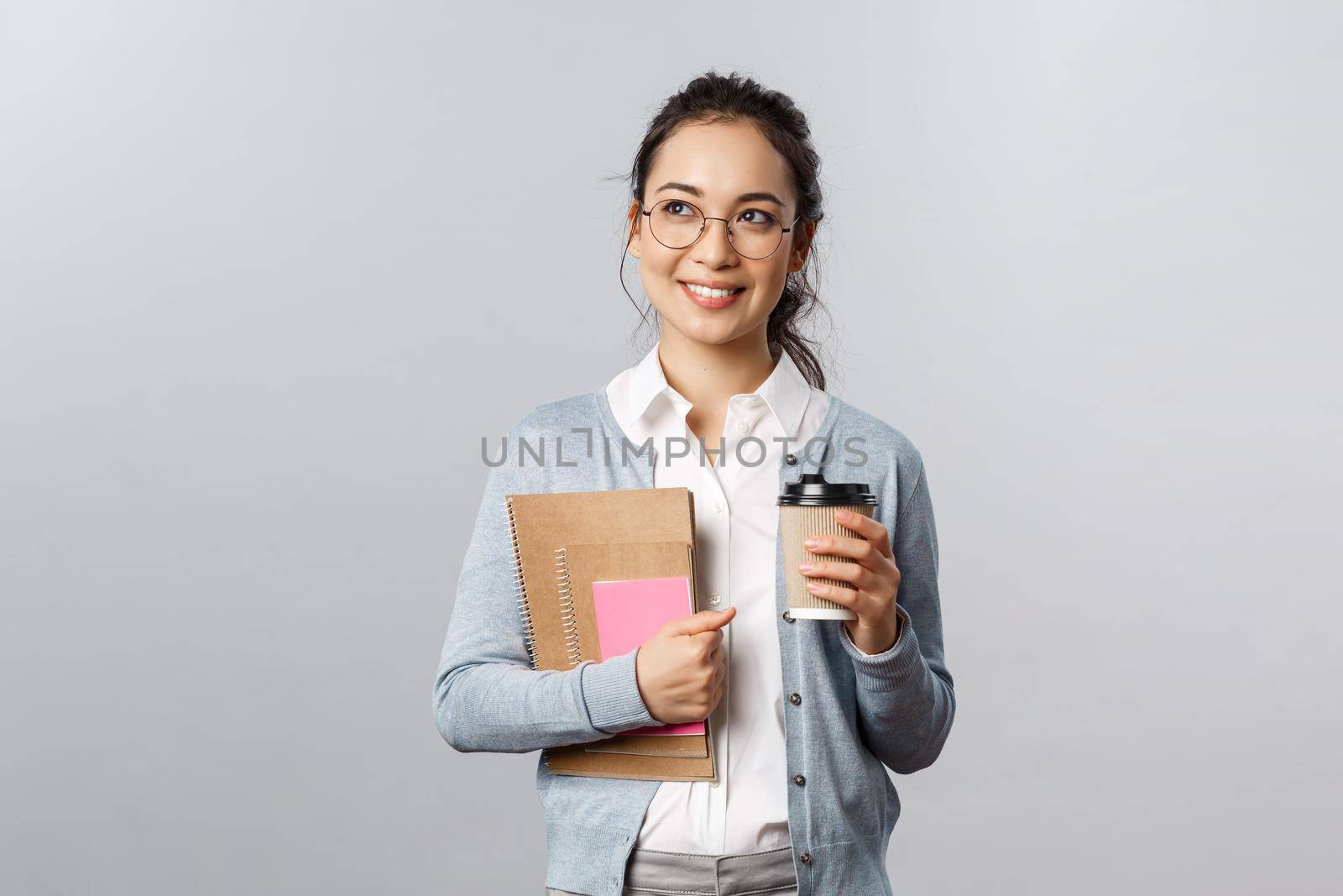 Education, teachers, university and schools concept. Dreamy happy student carry books and notebooks, drinking take-away coffee, daydreaming, smiling thoughtful looking up.