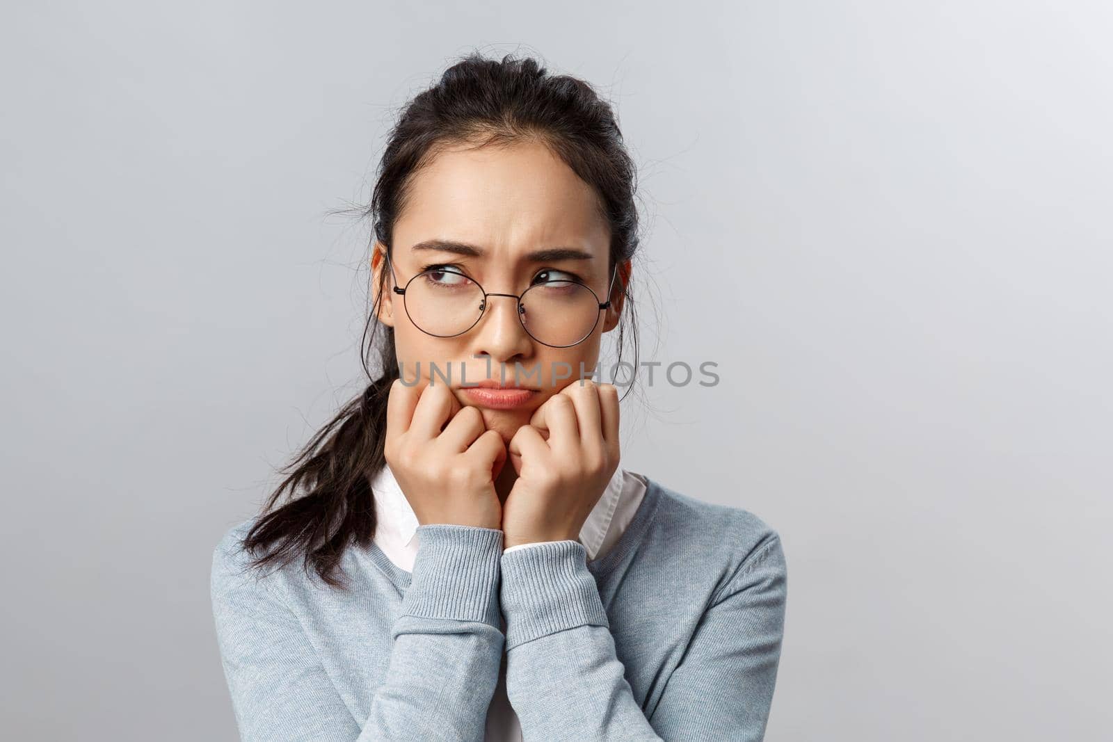 Close-up of gloomy offended young silly asian woman, sulking frowning upset, look left with envy or regret, have hard feelings, insulted of unfair situation happened her, stand grey background by Benzoix