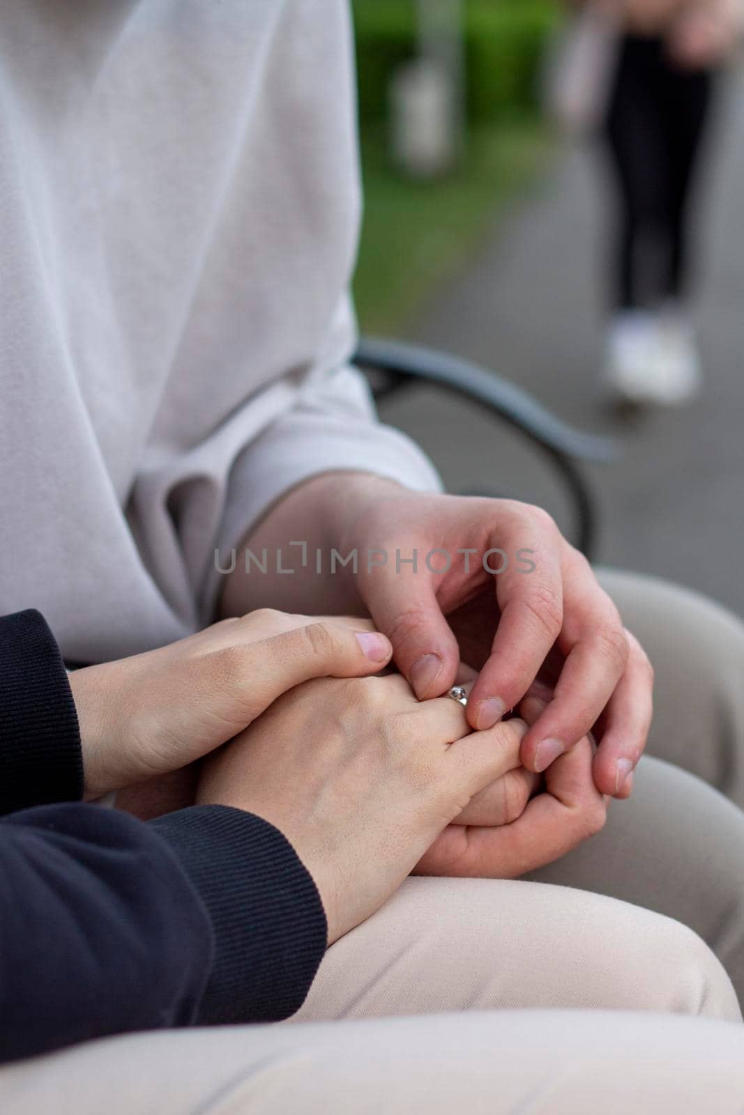 people, holidays, engagement and love concept - close up of engaged couple holding hands with diamond ring over holidays lights background