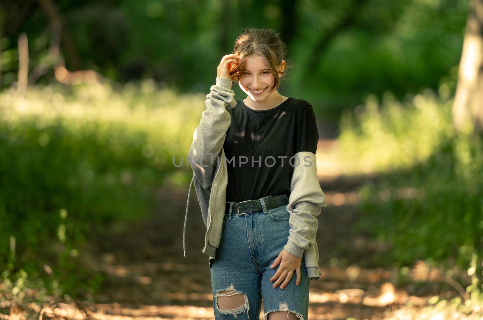 Pretty girl teenager smiling in green field with sunshine outdoors. Beautiful young female person at nature