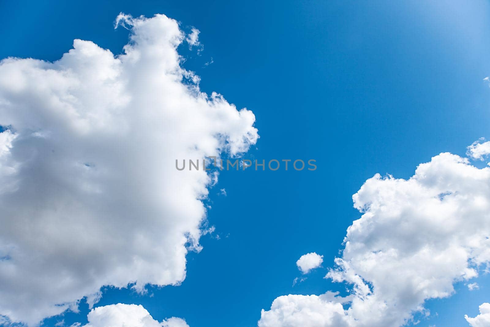 White cumulus clouds on bright blue sky by kisika