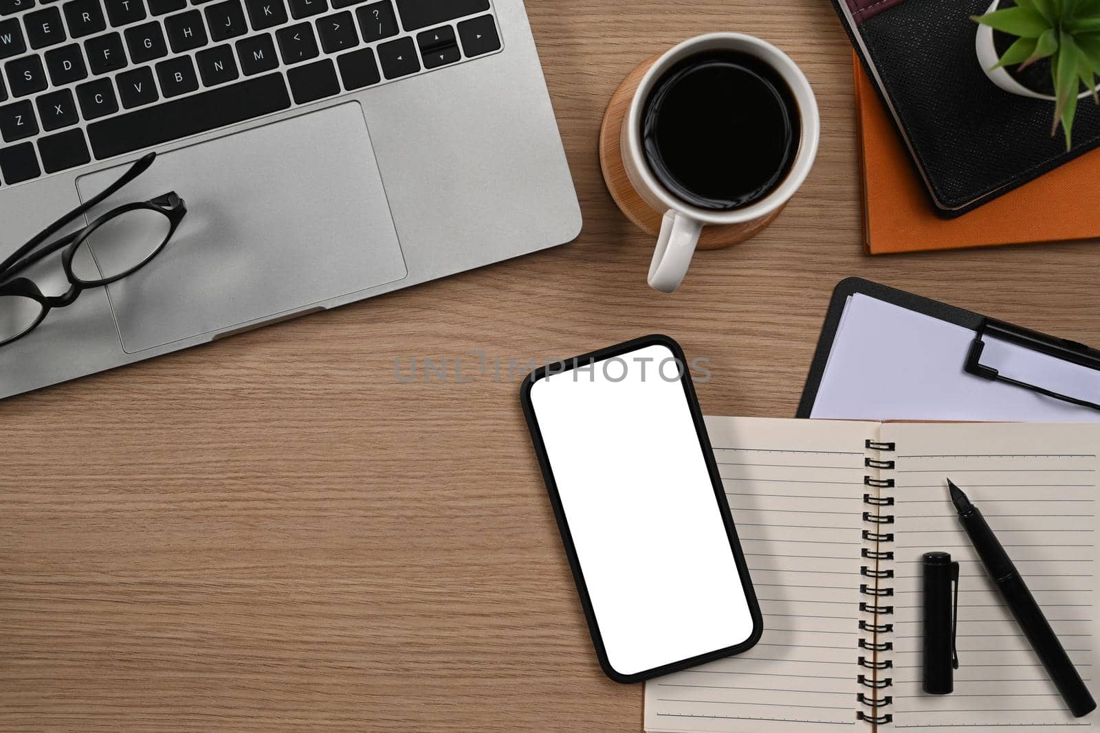 Laptop computer, smart phone, glasses, notebook and coffee cup on wooden background. Top view.