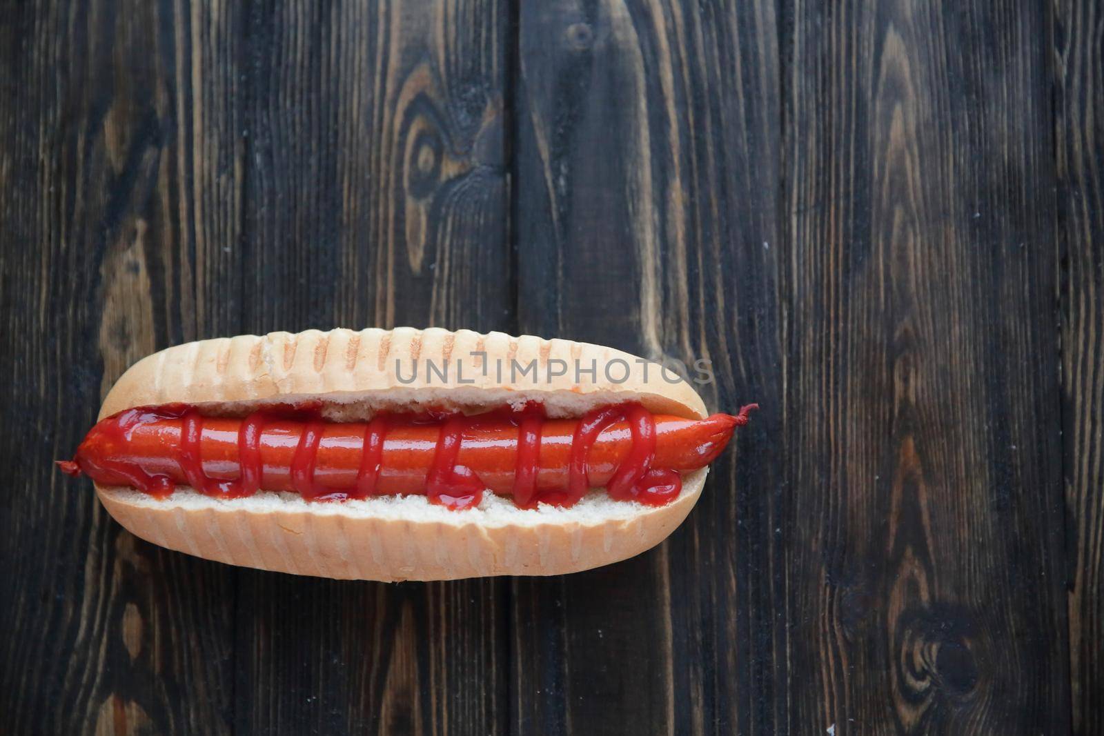 hot dog with smoked sausage on dark wooden background.photo with copy space.