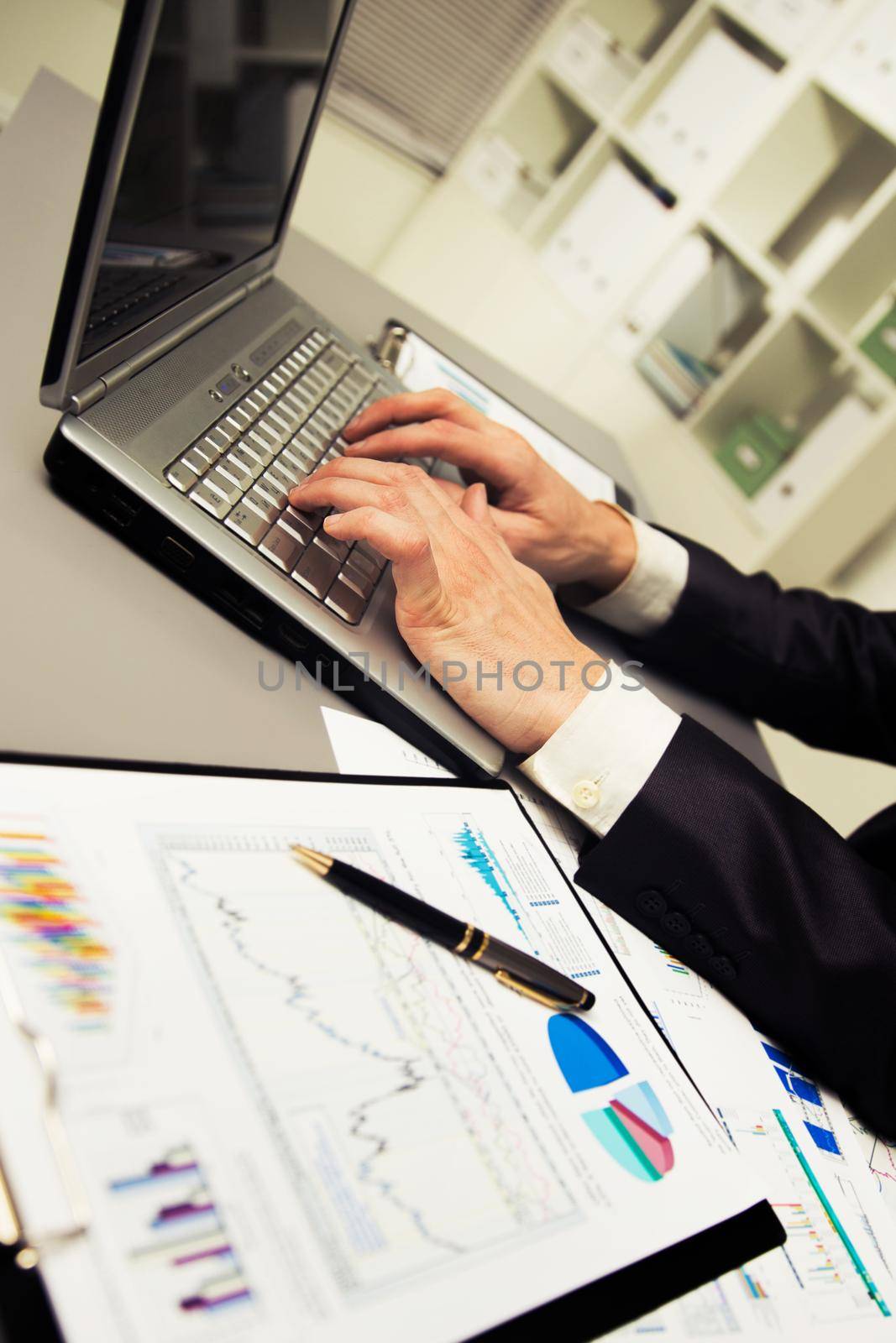Person Typing on a modern laptop in an office by SmartPhotoLab