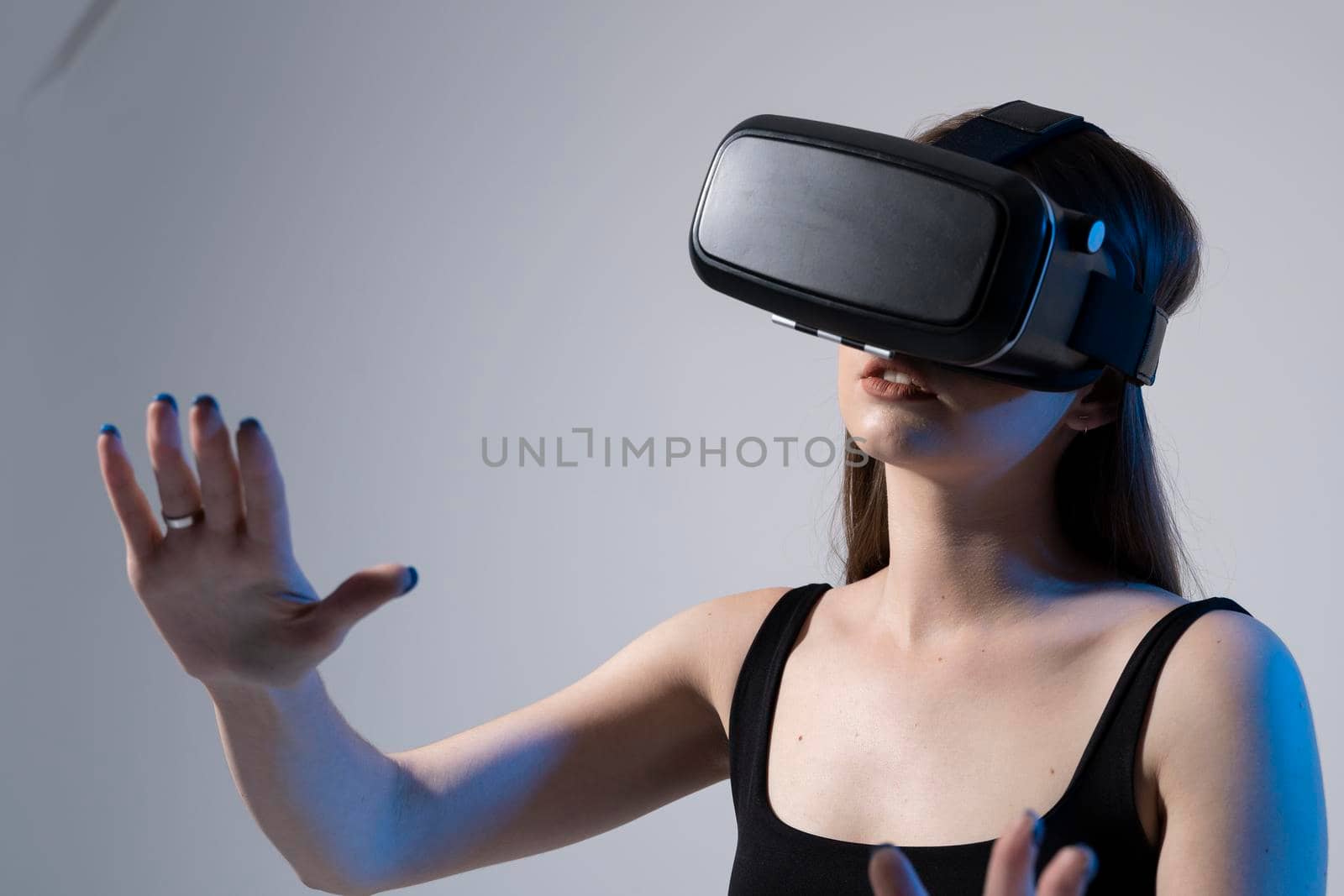 Amazed happy brunette girl in black t-shirt getting experience using VR headset glasses of virtual reality and exploring a new cyber worlds. by vovsht