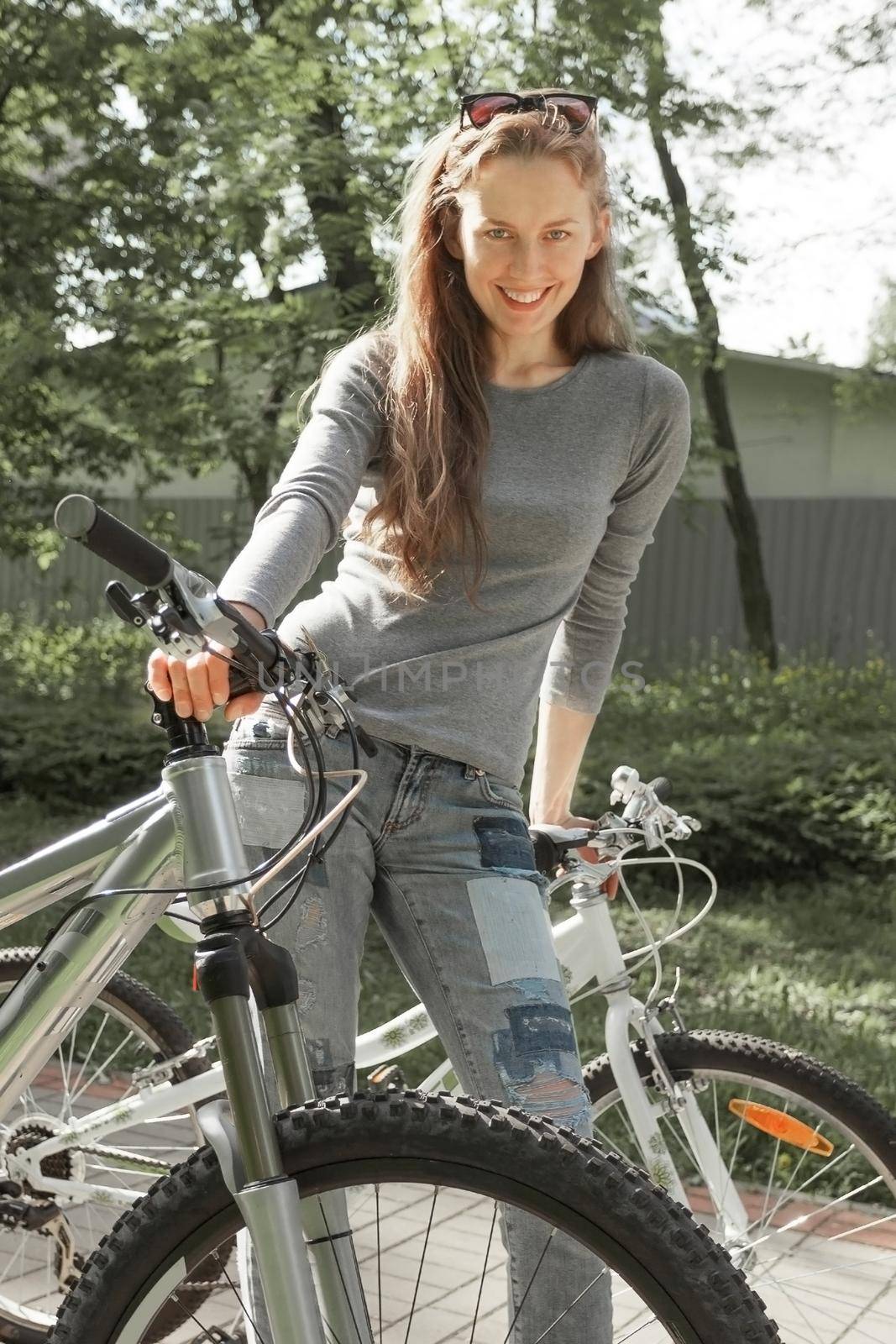 smiling young woman with bike standing in city Park. city life