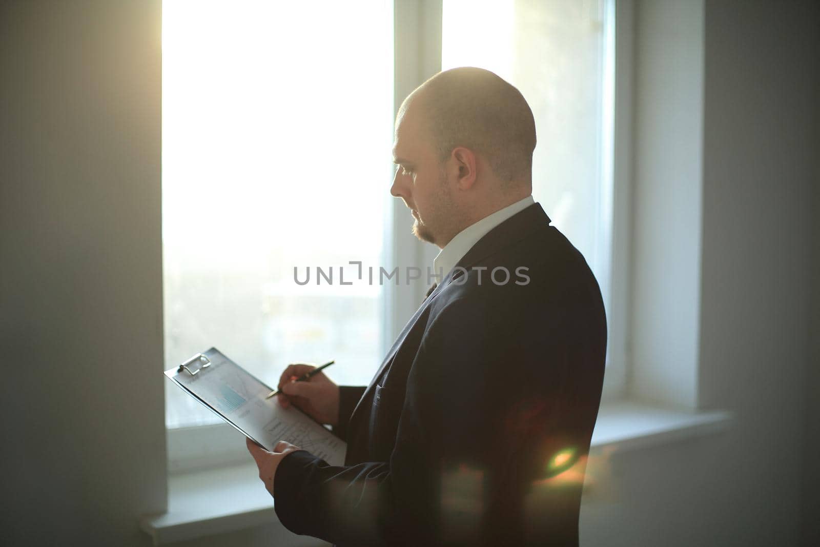 adult businessman signing document standing near office window.photo with copy space