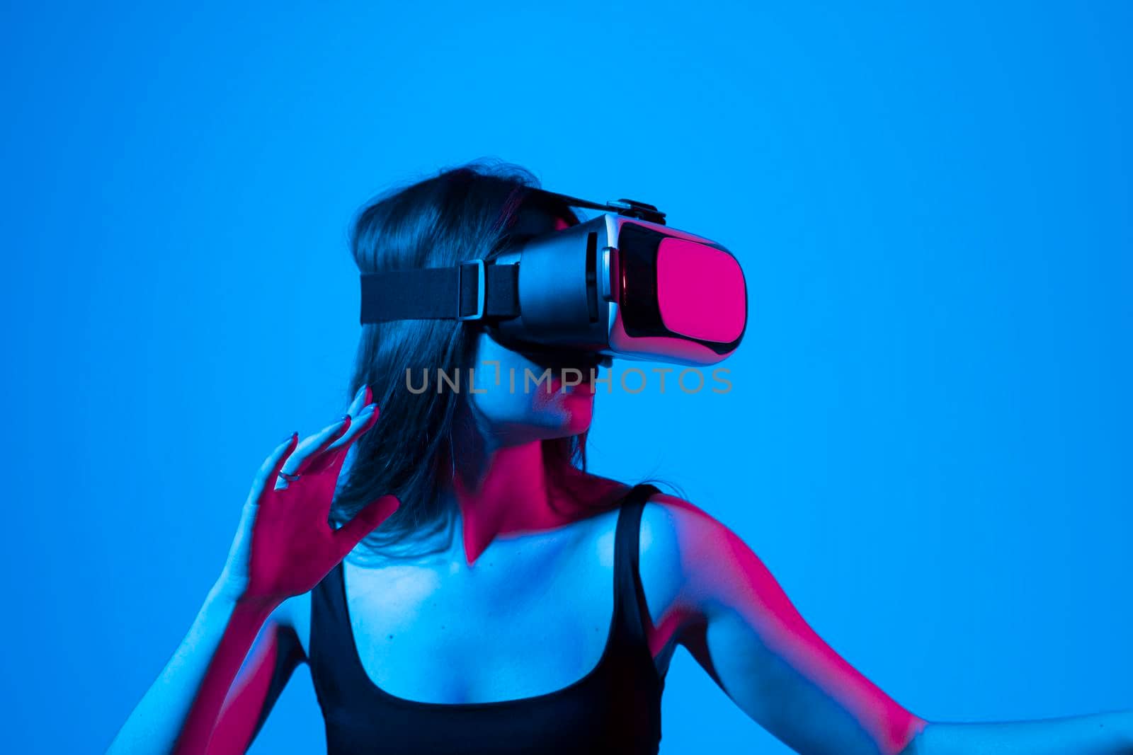 Amazed female in VR glasses headset interacting with network while having virtual reality experience. Future technology concept. Metaverse. by vovsht