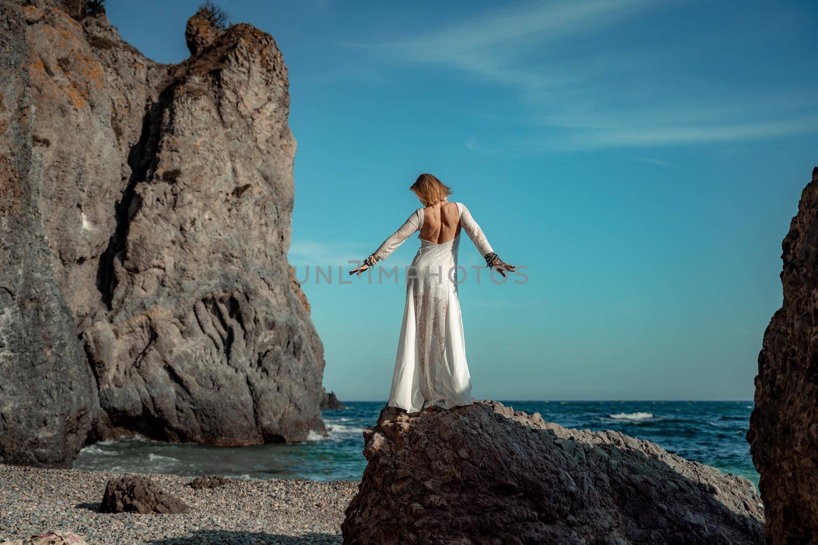 Middle aged woman looks good with blond hair, boho style in white long dress on the beach decorations on her neck and arms