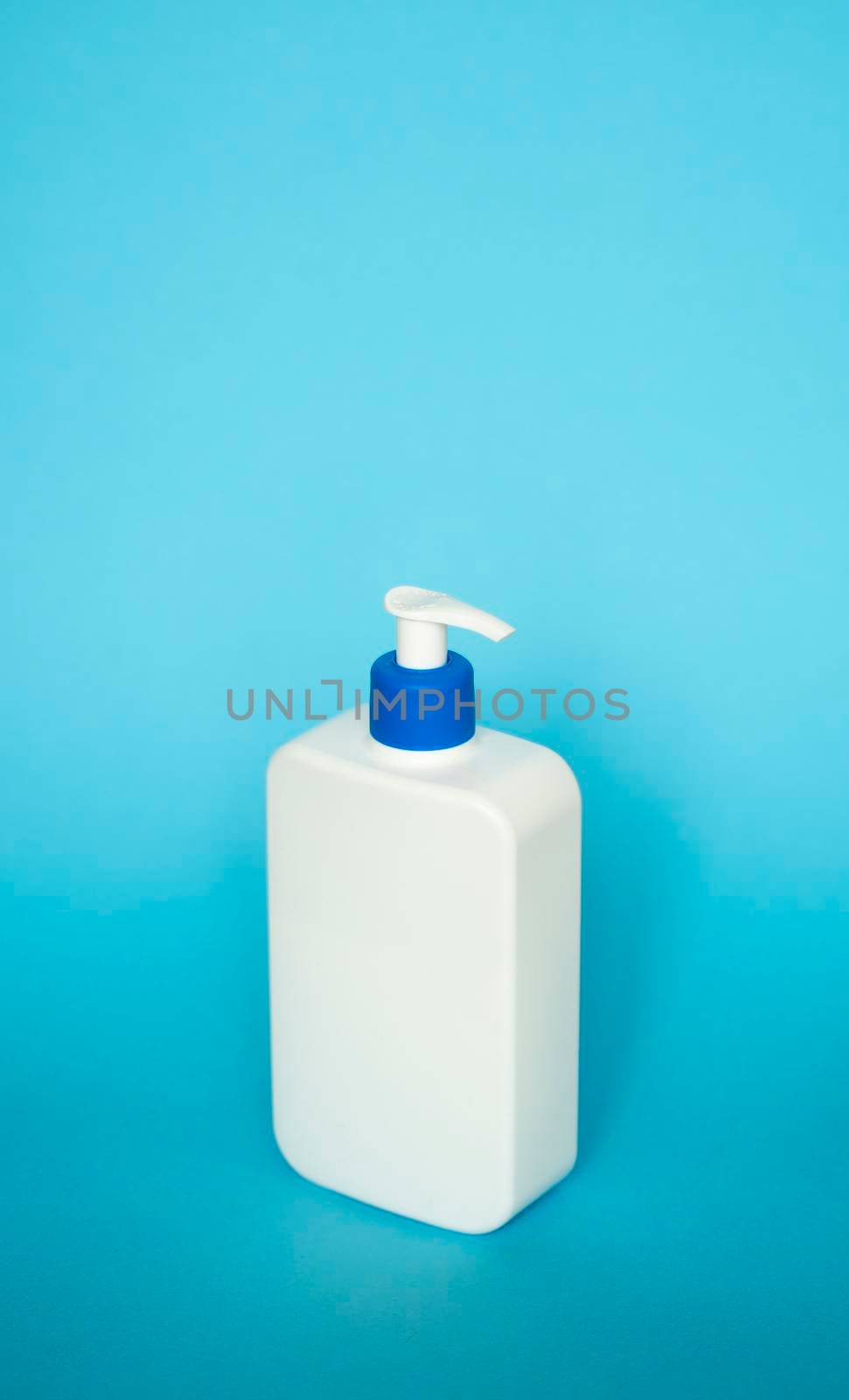 Large white plastic bottle with pump dispenser as a liquid container for gel, lotion, cream, shampoo, bath foam on blue background. by vovsht