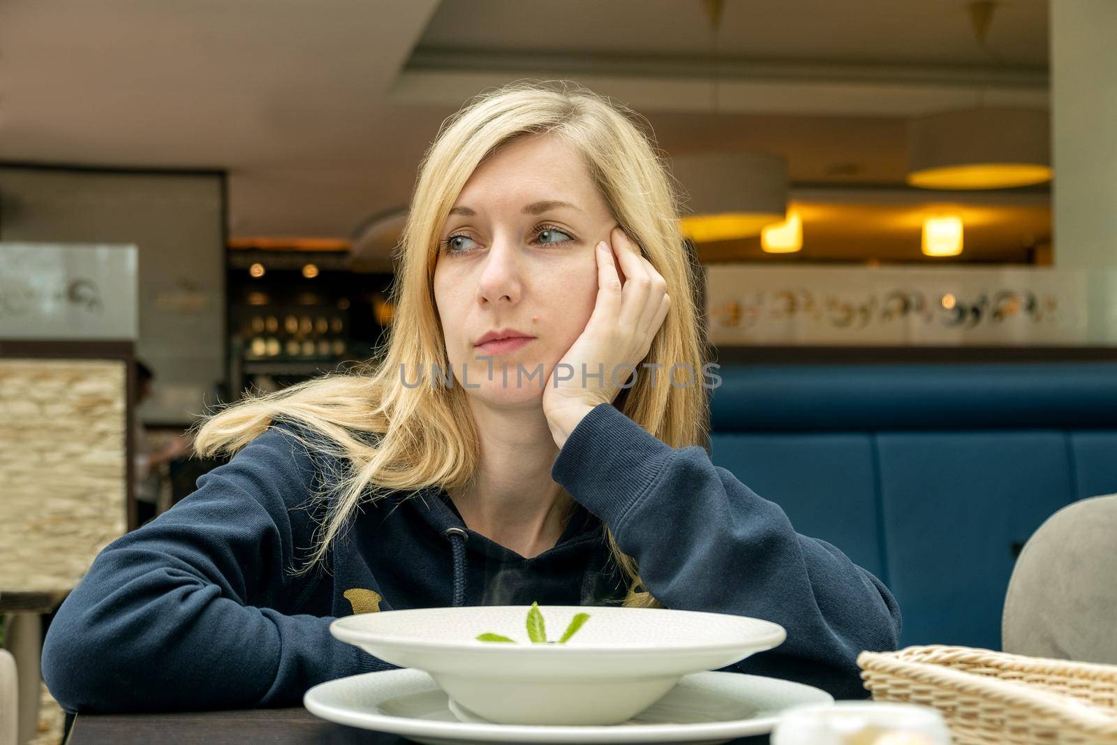 Blonde woman in a cafe with a plate of food by OlgaGubskaya