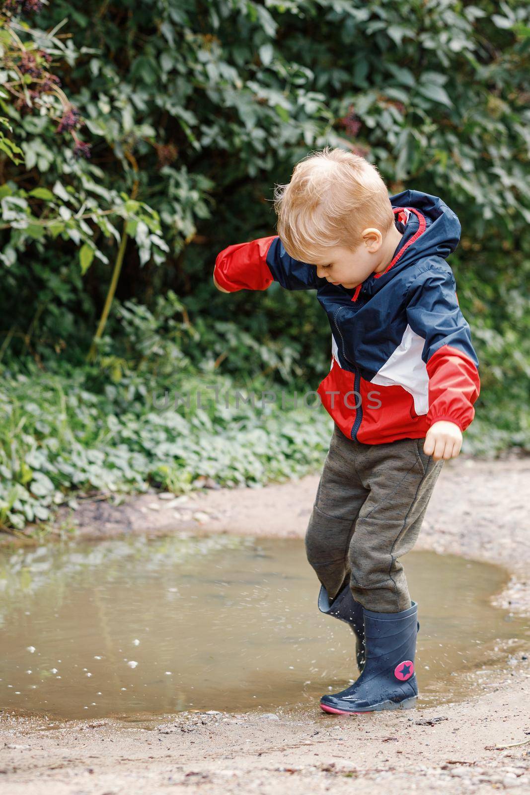 Toddler jumping in pool of water at the summer or autumn day. by Lincikas