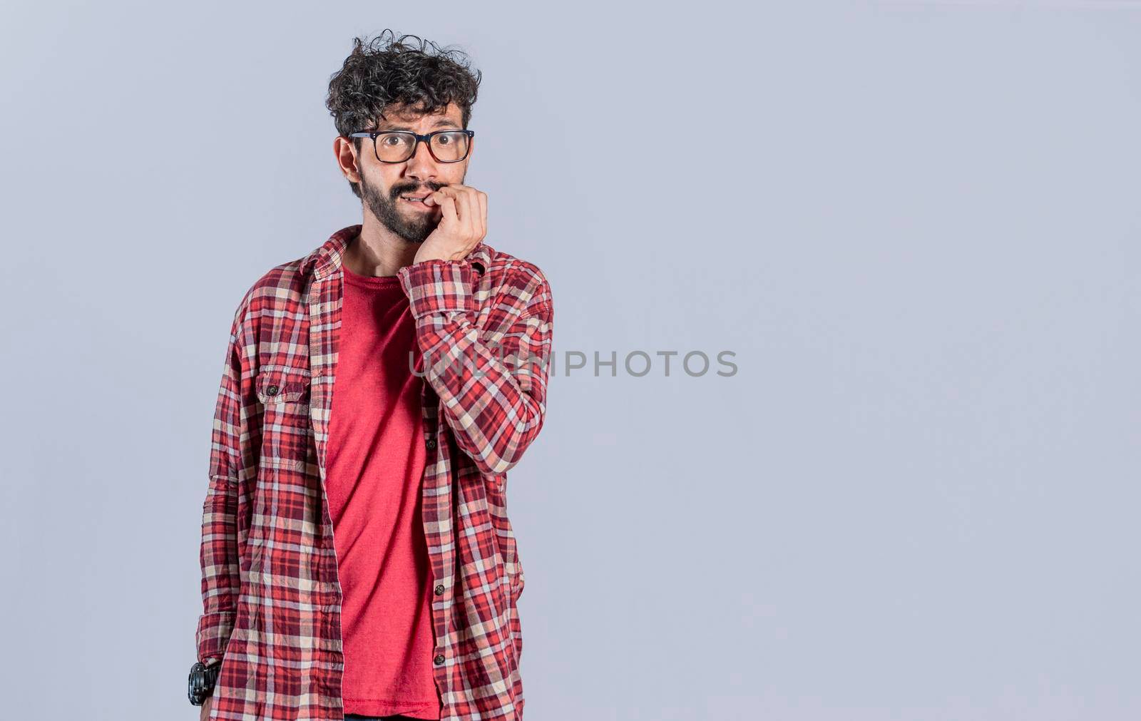 Nervous young male with worried expression, bites nails and looks anxiously. Guy with worried expression on isolated background, nervous man concept