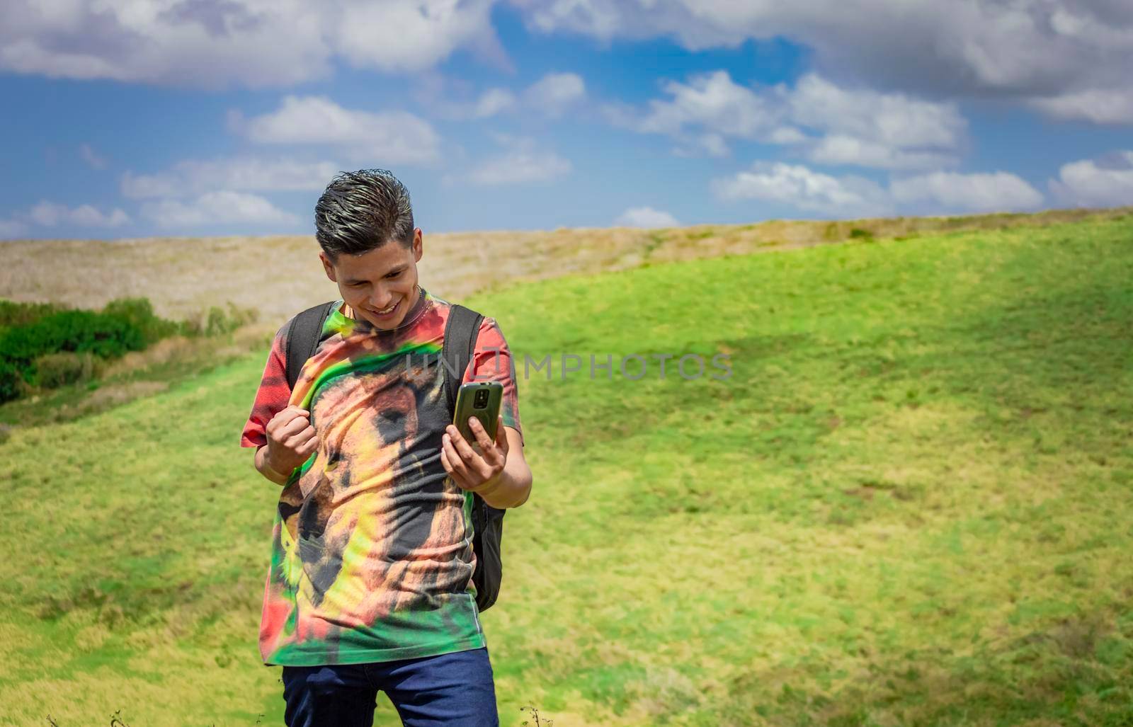 cheerful guy taking a photo in the field, young man taking photos in the field with his cell phone