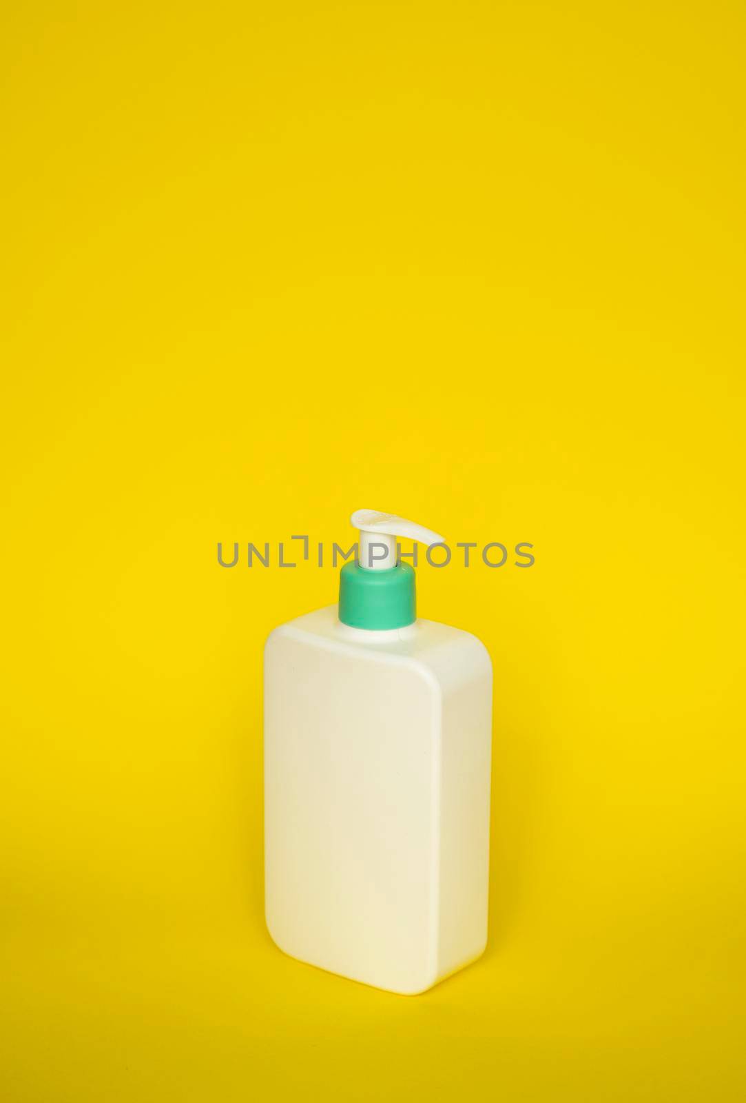 Shampoo or hair conditioner bottle with dispenser pump on yellow background