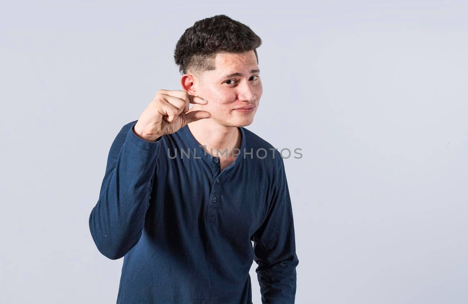 Man showing a small amount with his fingers, young man gesturing with his hand showing something small size with his fingers. Person measuring something with fingers