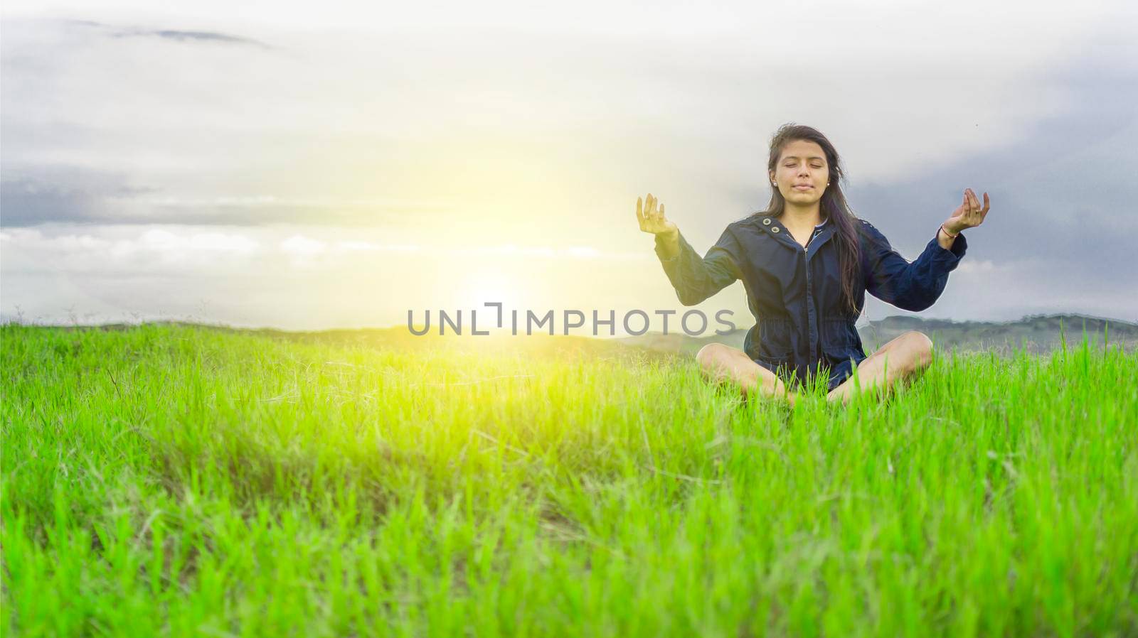 Woman in the field sitting meditating, woman doing yoga in the cool field