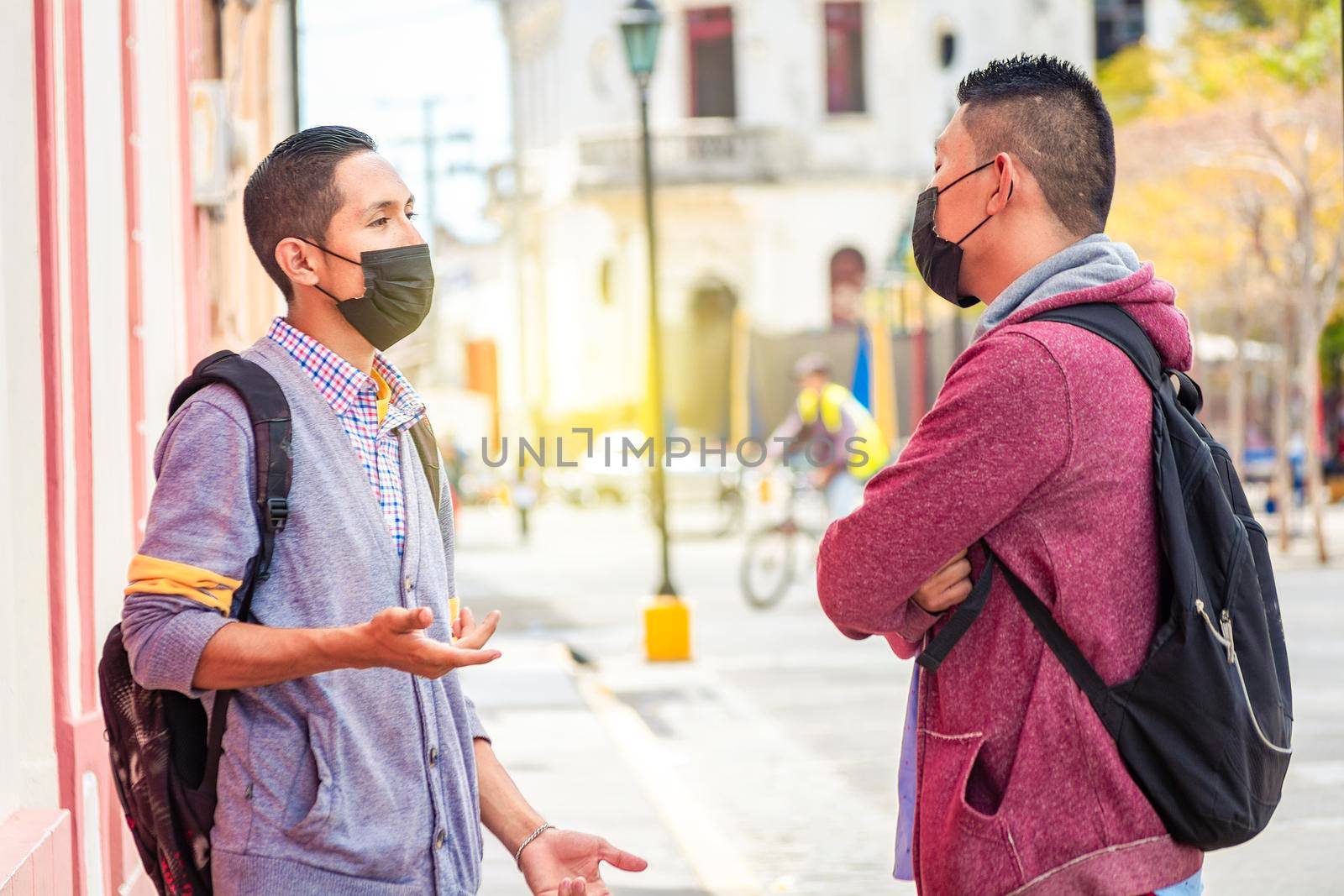 Two young people with mask having a conversation outdoors, two friends with face mask having a conversation, concept of conversation and social distance