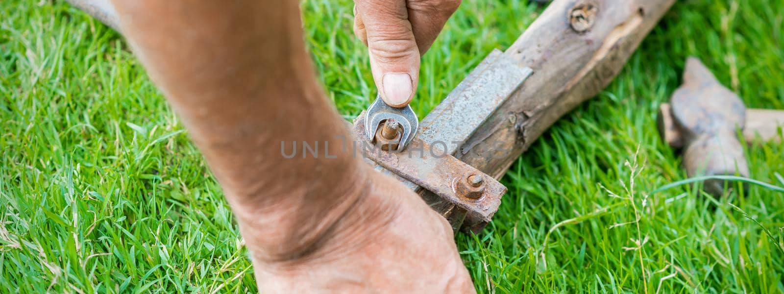 hand of an elderly man twisting the nut with a wrench outdoors. Repair by wrench.