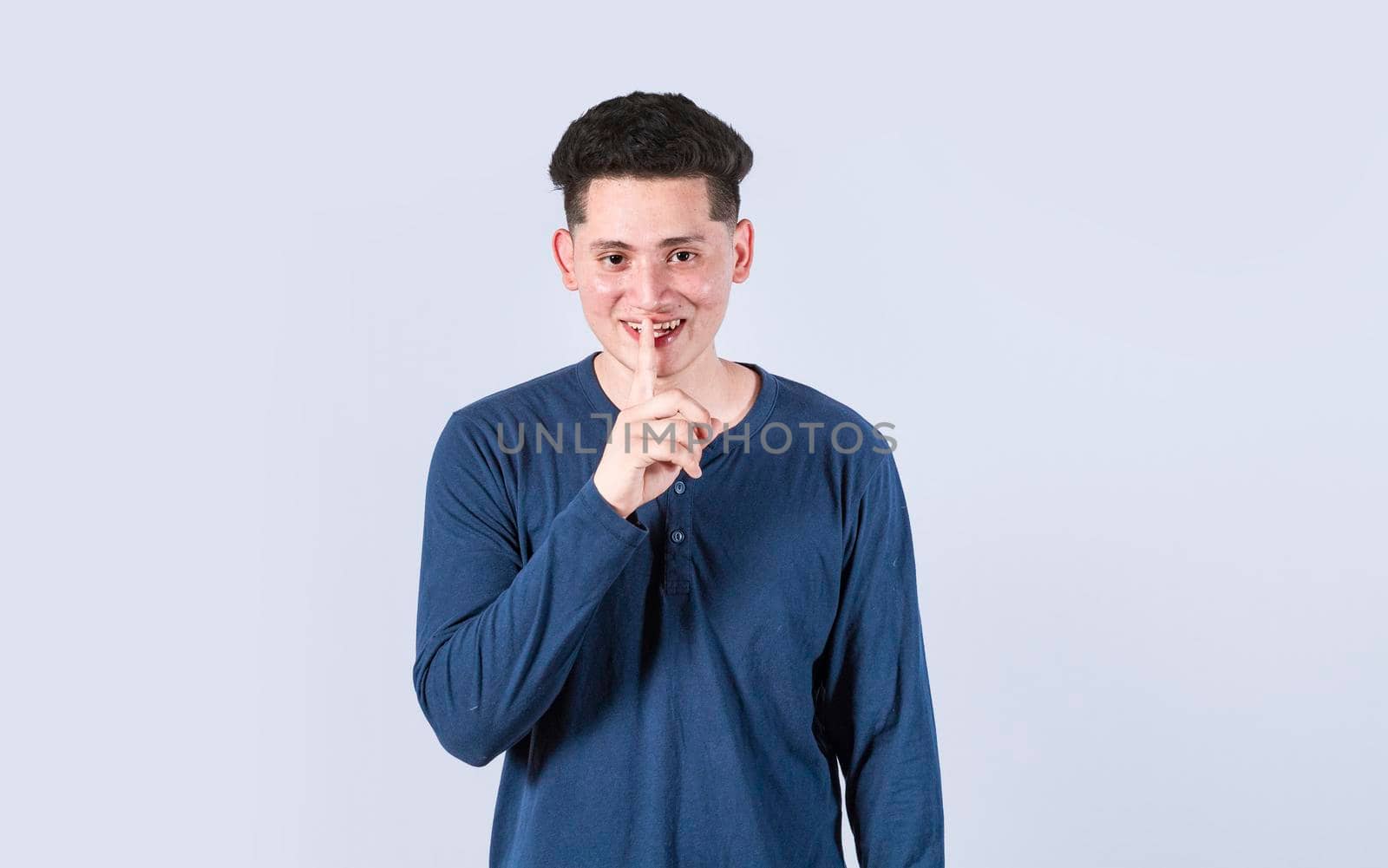 Man gesturing keep quiet, Guy smiling with finger on mouth showing hush gesture, Attractive male whispering silence