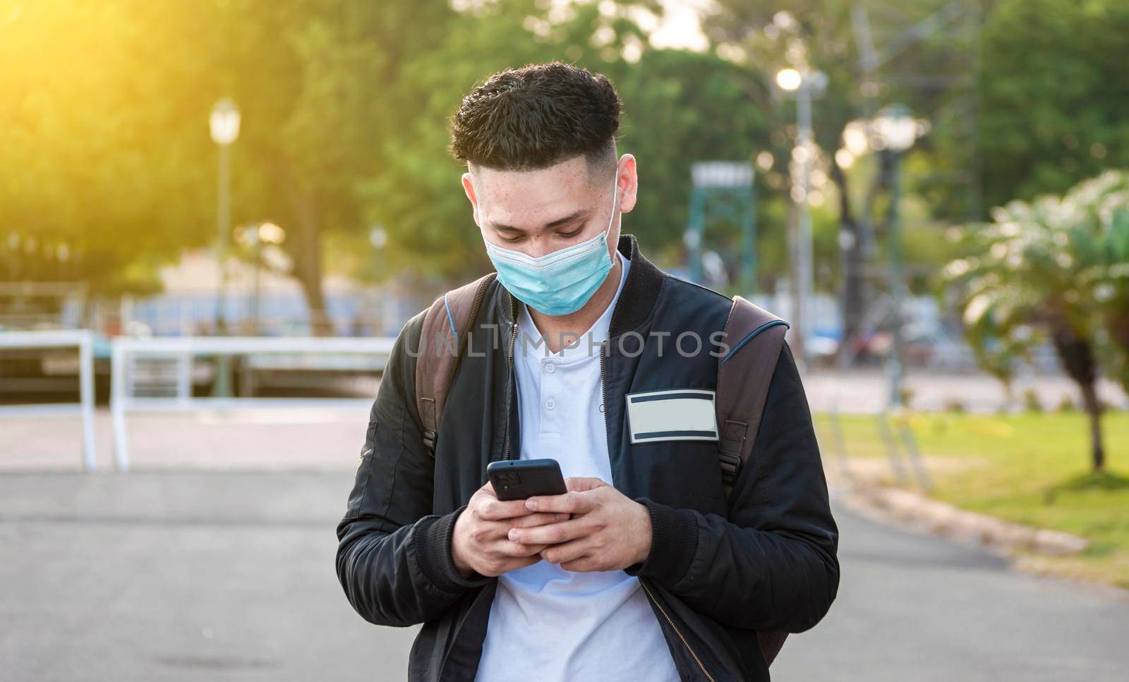 Handsome guy texting with his phone, Handsome young man in face mask texting with his phone, Handsome man texting on his phone by isaiphoto