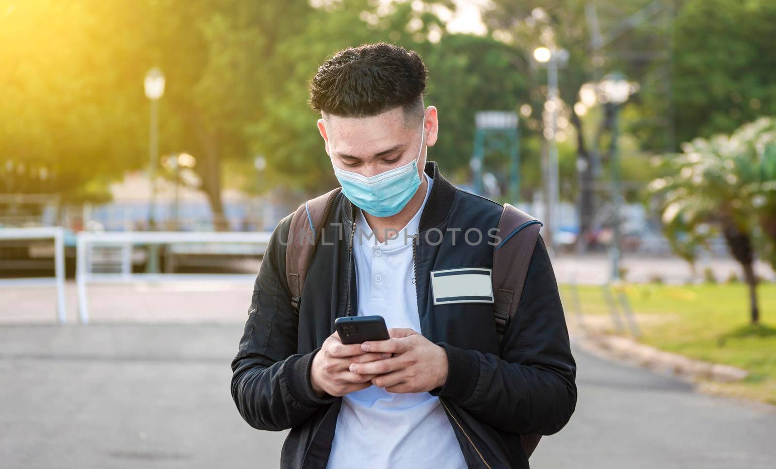 Handsome guy texting with his phone, Handsome young man in face mask texting with his phone, Handsome man texting on his phone