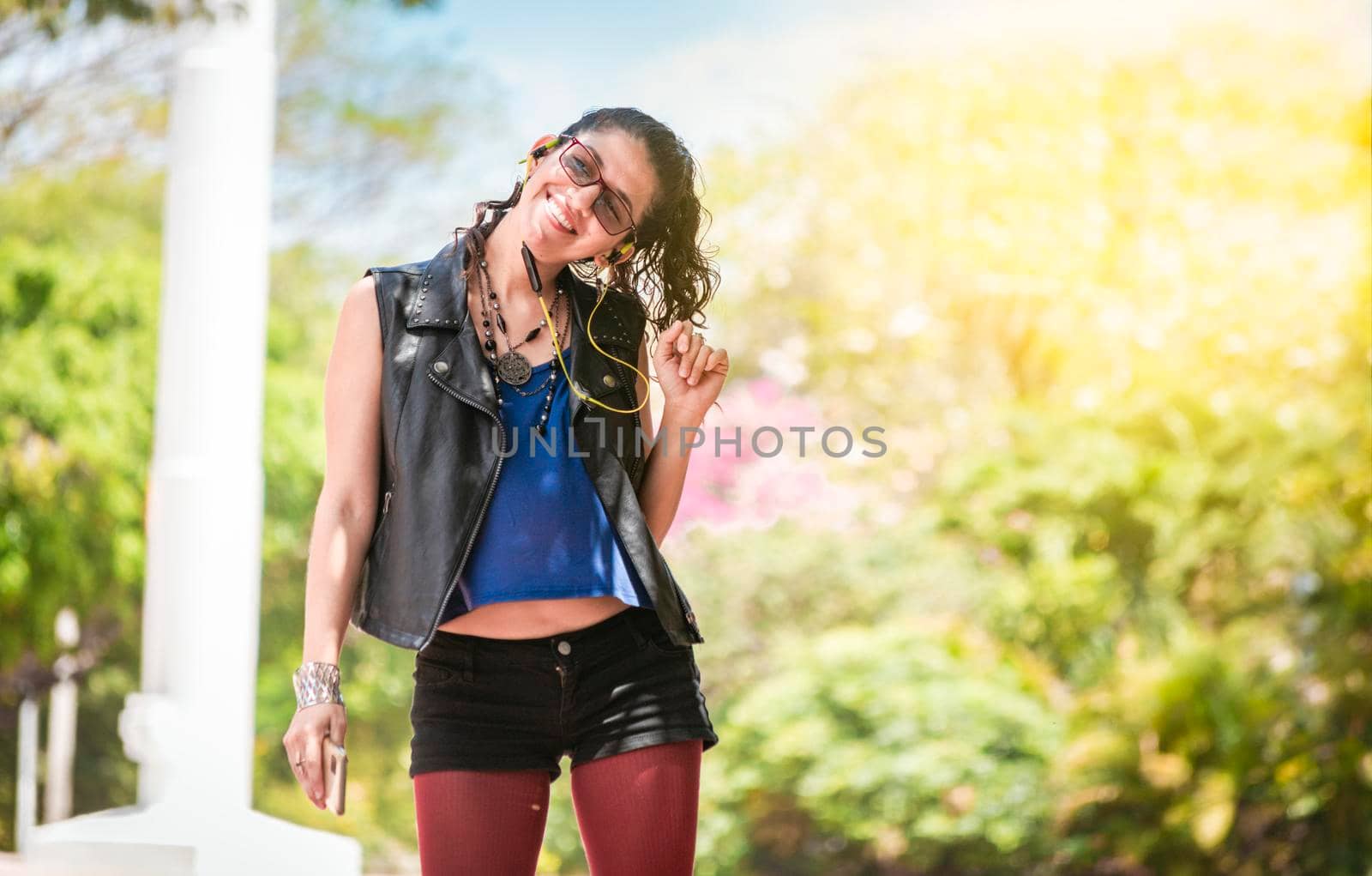 Latin girl listening to music outside, Urban girl enjoying music with headphones, happy woman listening to music outside, concept of girl listening to music