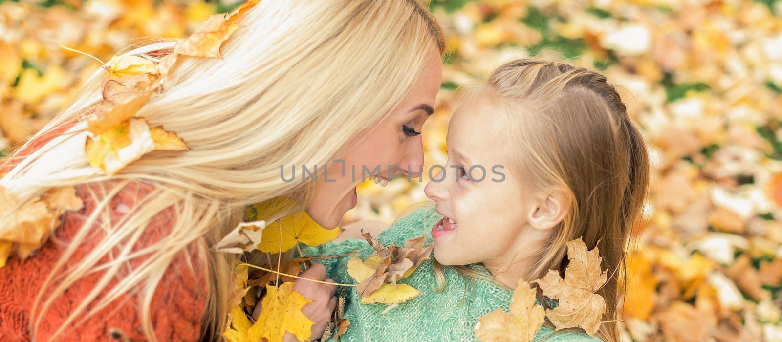 Beautiful young caucasian mother playing with her little child in the autumn park