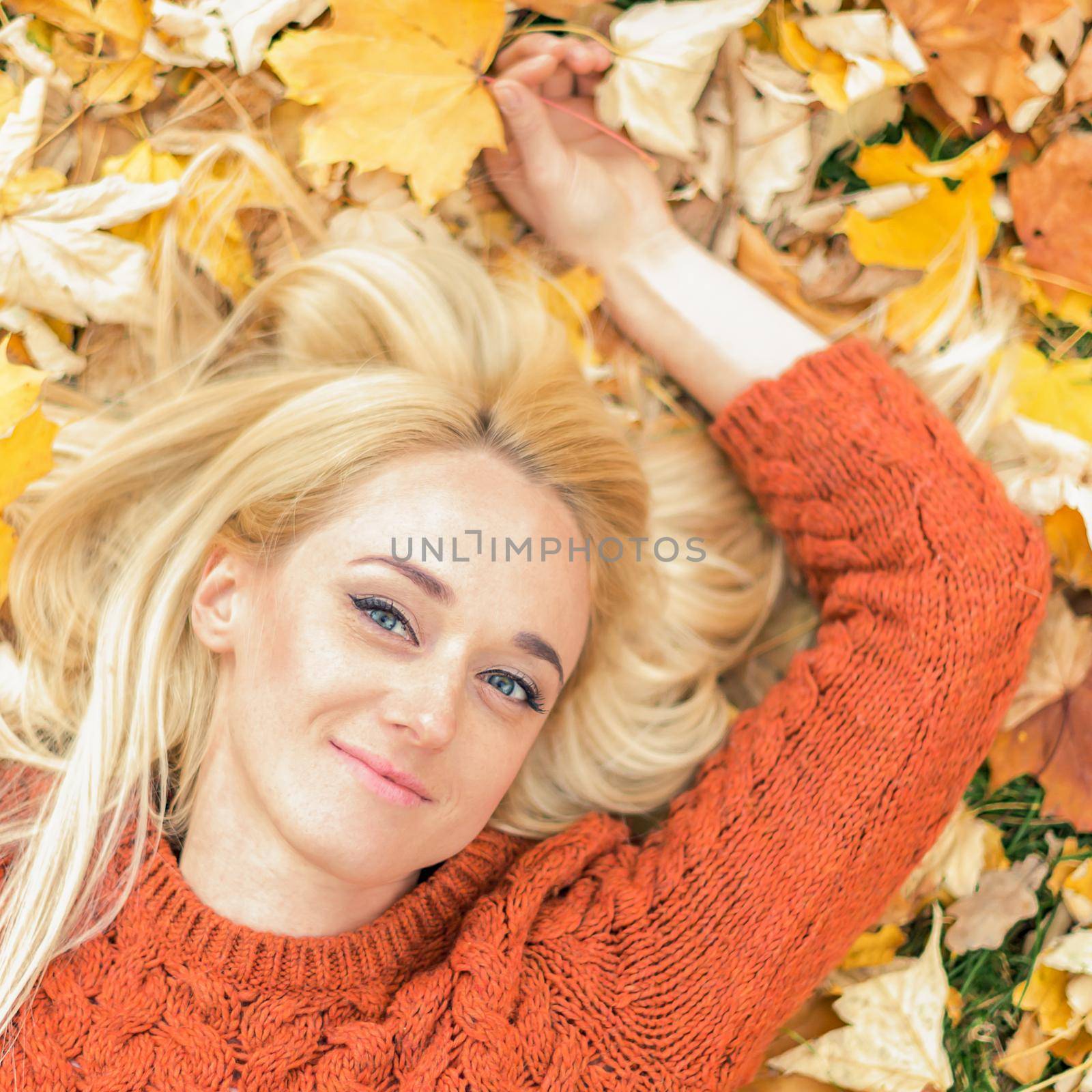 Woman lying down on yellow leaves by okskukuruza