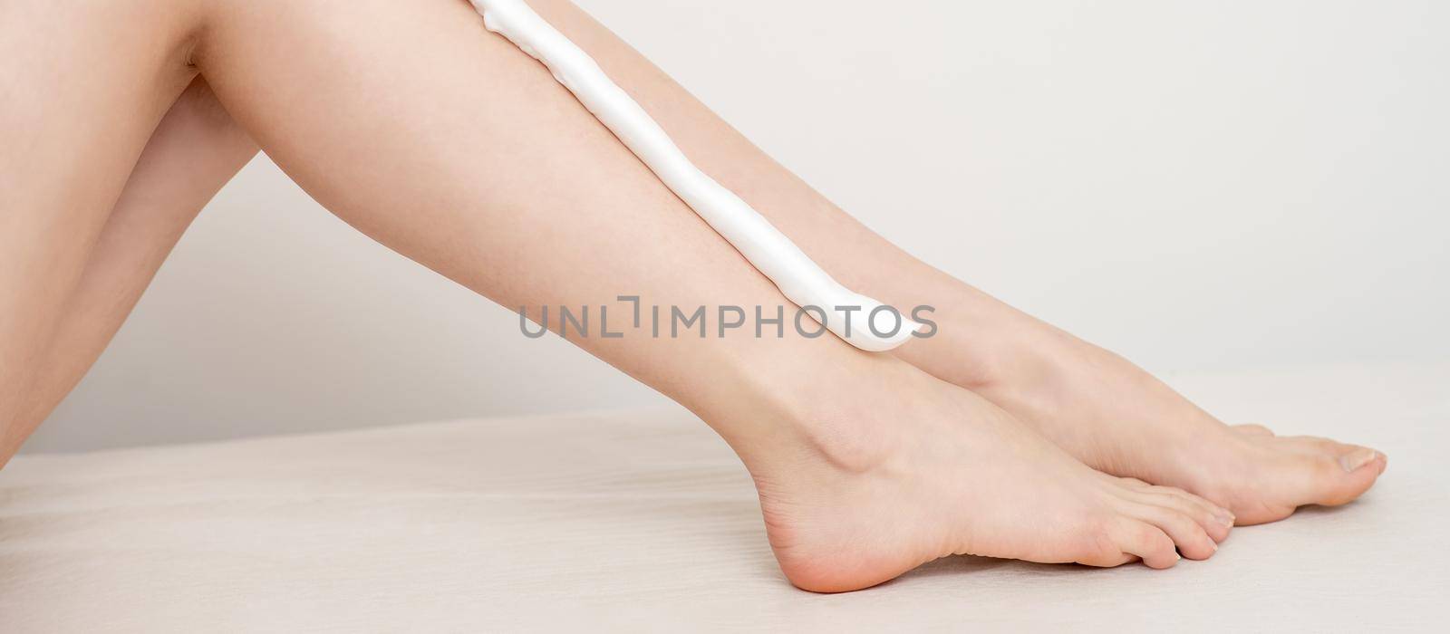 Female nice long slim bare legs with shaving foam on white background