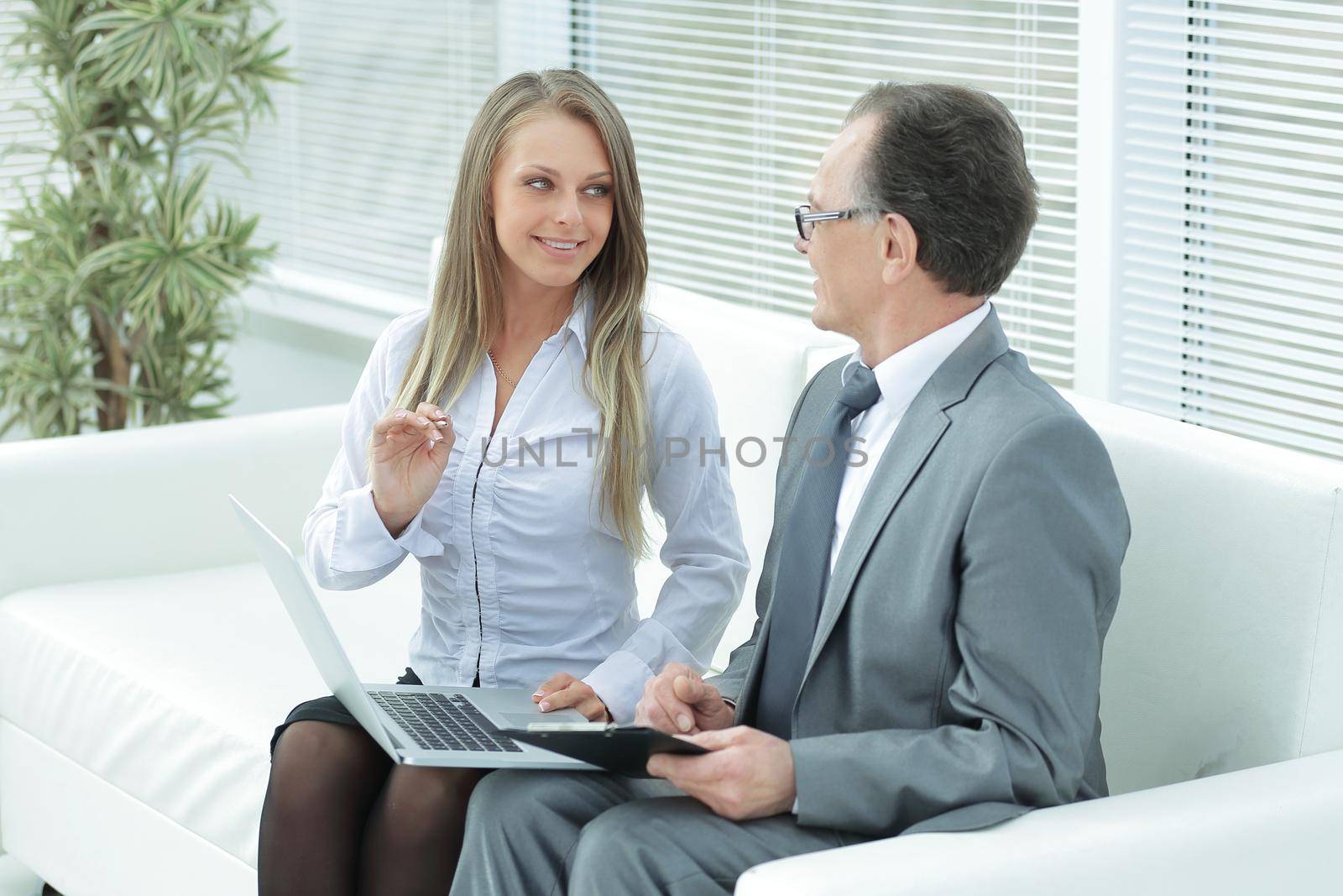 senior businessman and assistant using a laptop sitting in the lobby of the office.photo with place for text
