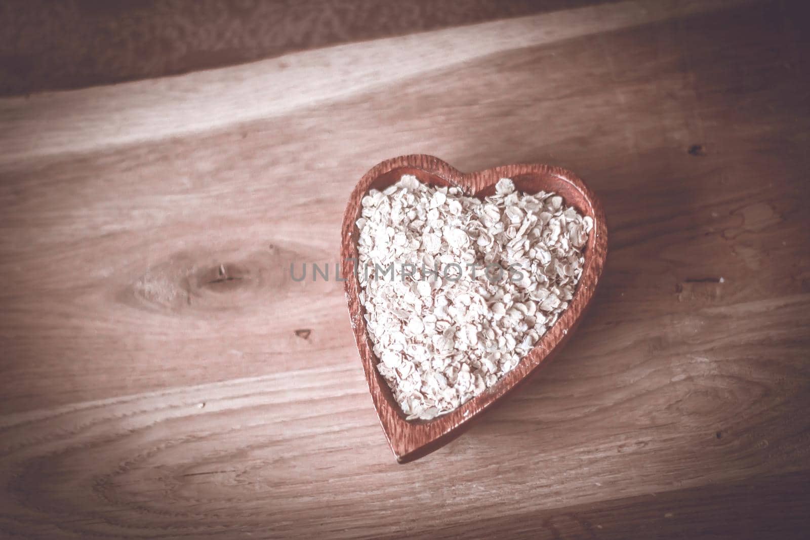 useful oat flakes in a wooden bowl on a wooden table