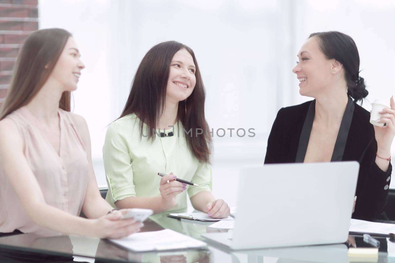 business woman discussing a document with a female employee when they share a Desk in the office by SmartPhotoLab