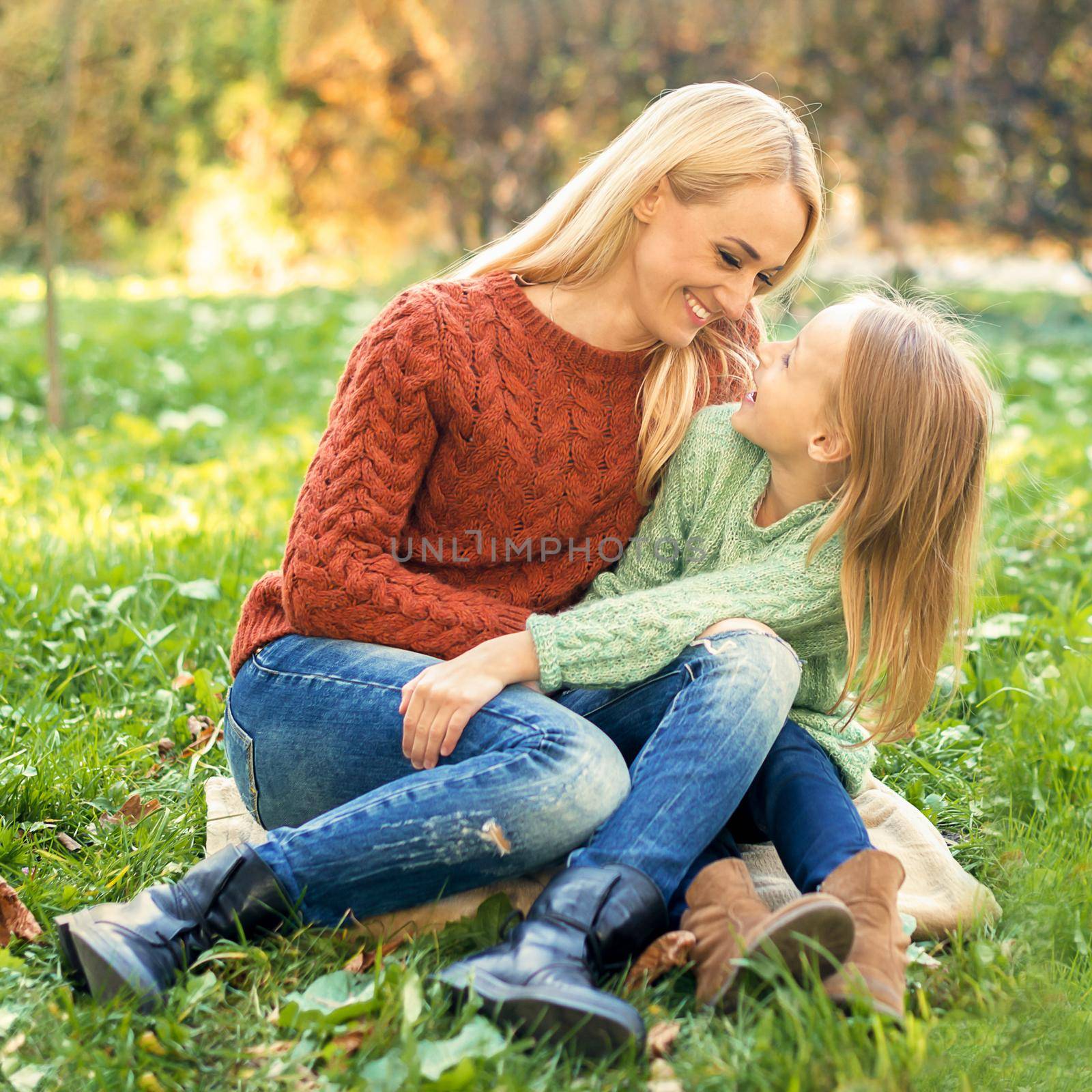 Happy smiling young caucasian mother and little daughter hugging each other outdoors. Happy family outdoor.