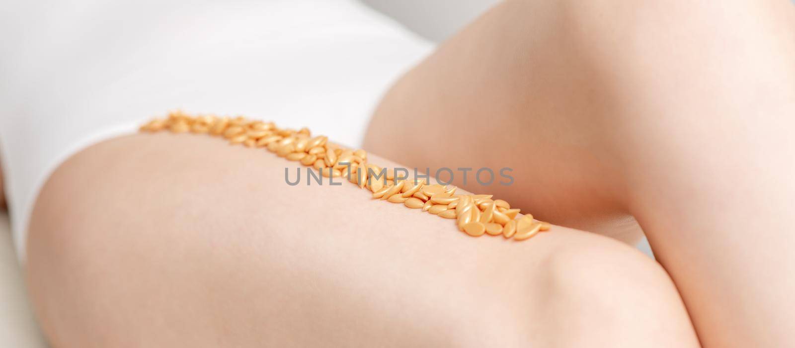 Wax beans or seed in row on legs of young woman lying on white background