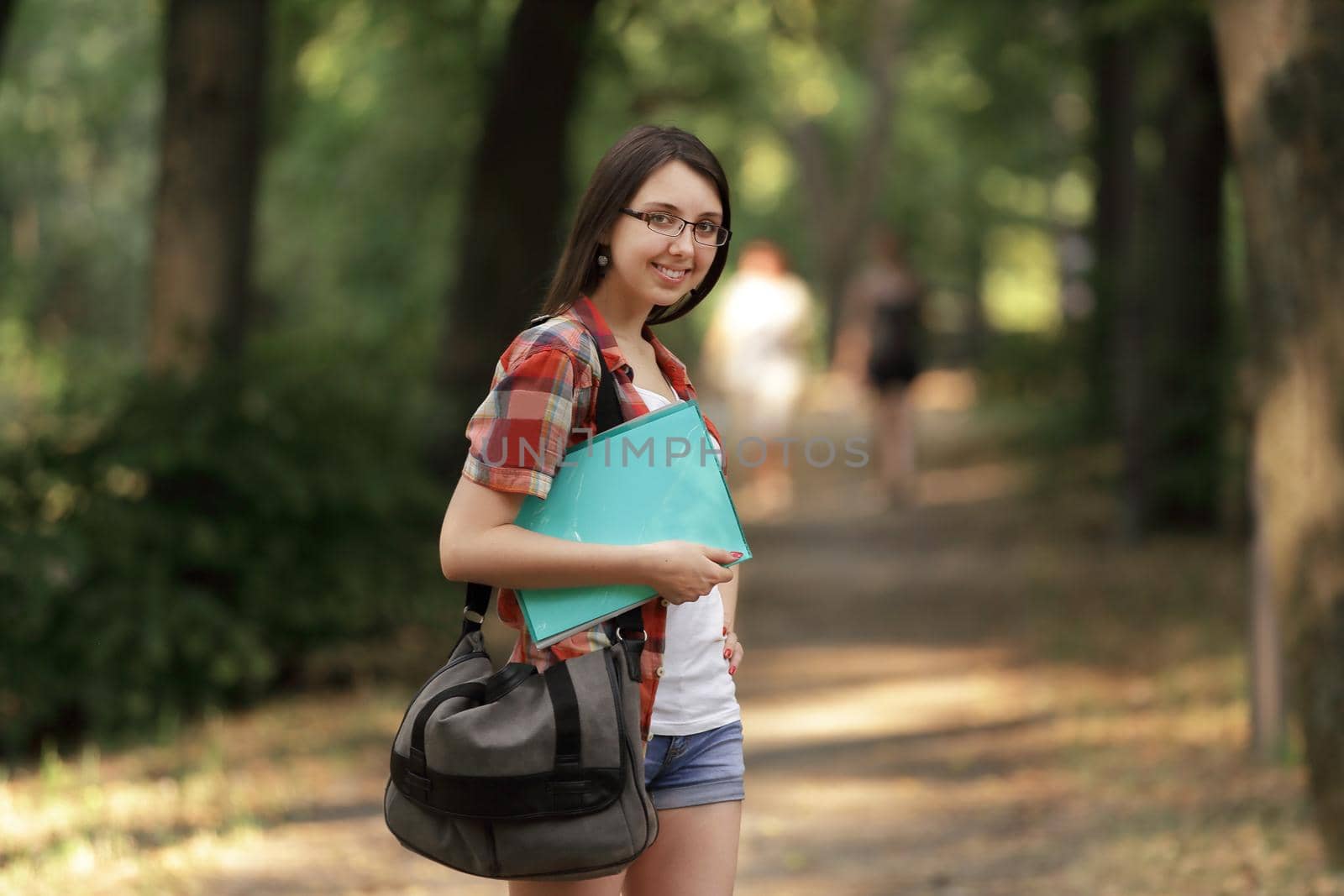 smiling student girl with a clipboard on the background of the Park.