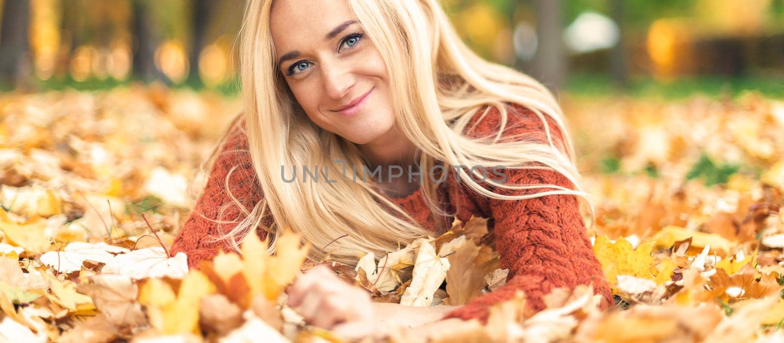 Woman lies down on leaves at the autumn park by okskukuruza