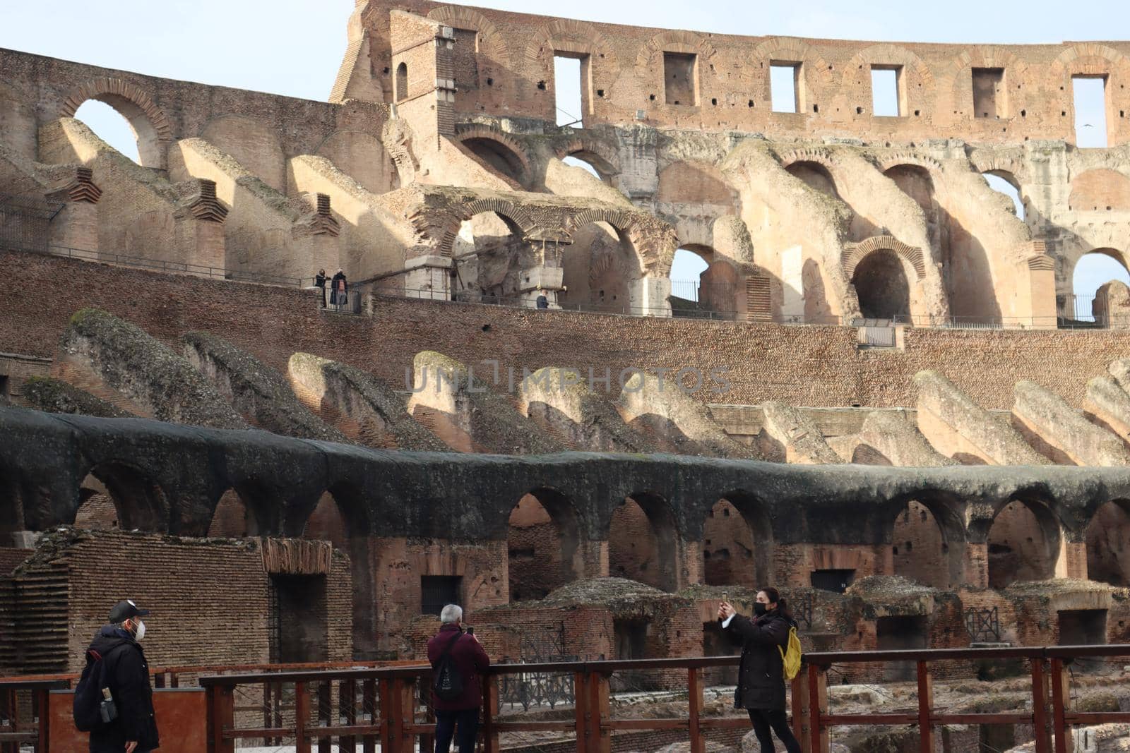 ROME, ITALY - February 05, 2022: Panoramic view around the Colosseum in city of Rome, Italy. Cold and gray sky in the background. Macro photography of the green parks with the old buildings.