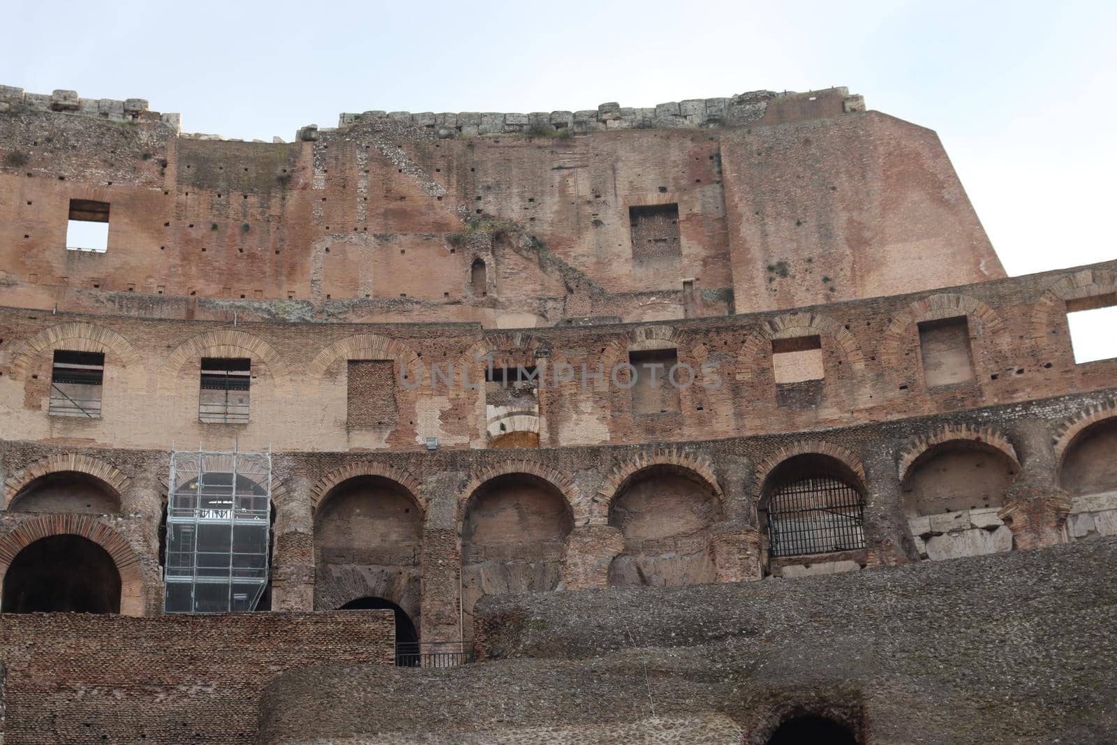 ROME, ITALY - February 05, 2022: Panoramic view around the Colosseum in city of Rome, Italy. Cold and gray sky in the background. Macro photography of the green parks with the old buildings.