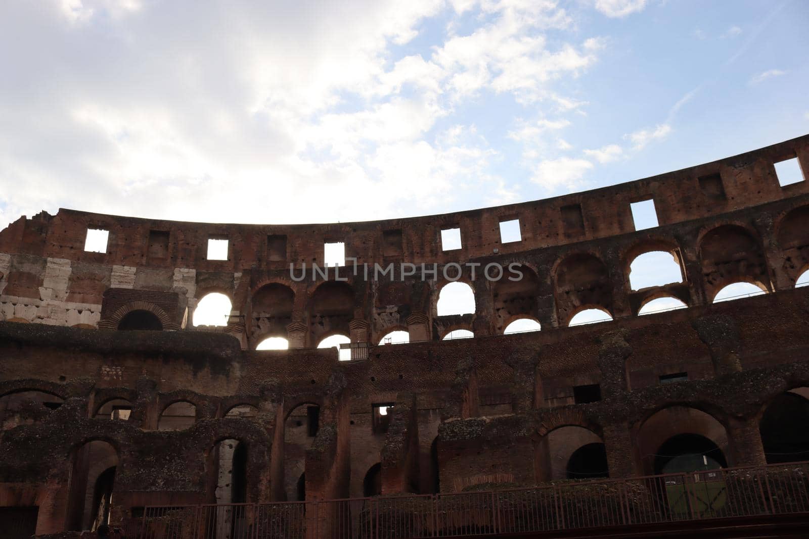 ROME, ITALY - February 05, 2022: Panoramic view around the Colosseum in city of Rome, Italy. Cold and gray sky in the background. Macro photography of the green parks with the old buildings.