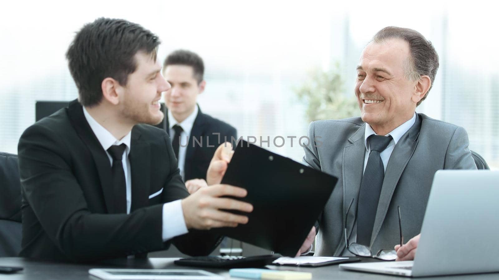 adult businessman discussing financial documents with a young colleague. by SmartPhotoLab