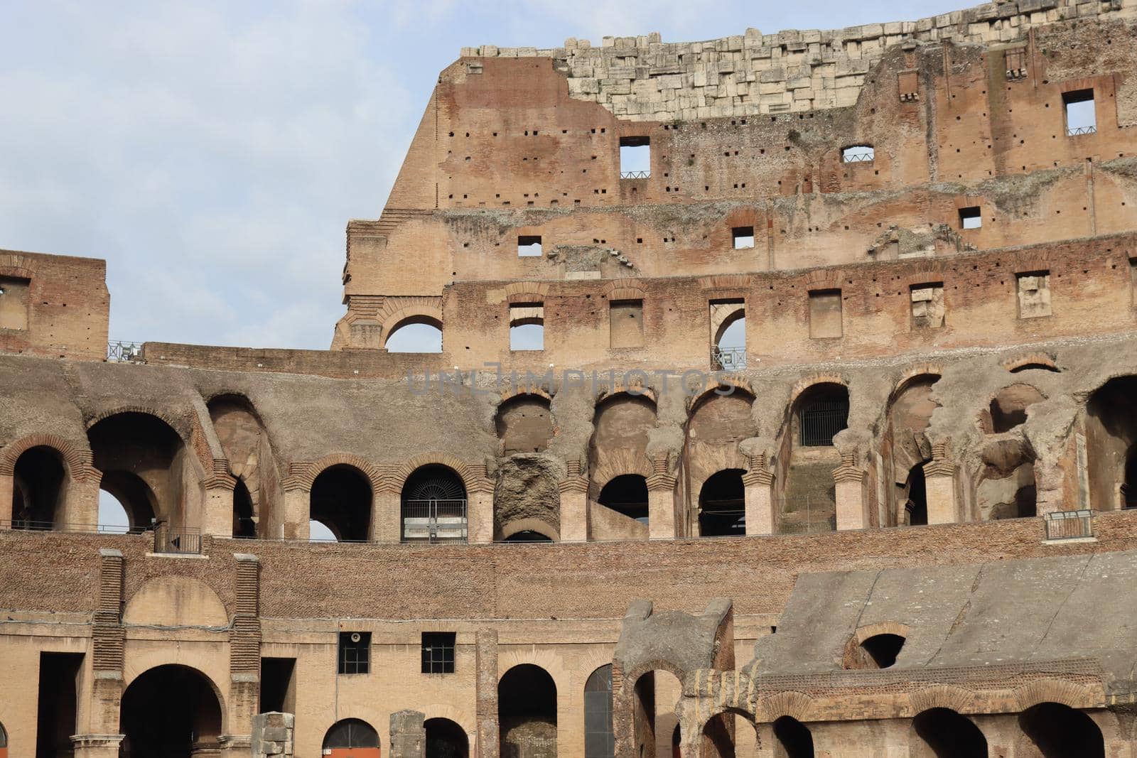 ROME, ITALY - February 05, 2022: Panoramic view around the Colosseum in city of Rome, Italy. Cold and gray sky in the background. Macro photography of the green parks with the old buildings.