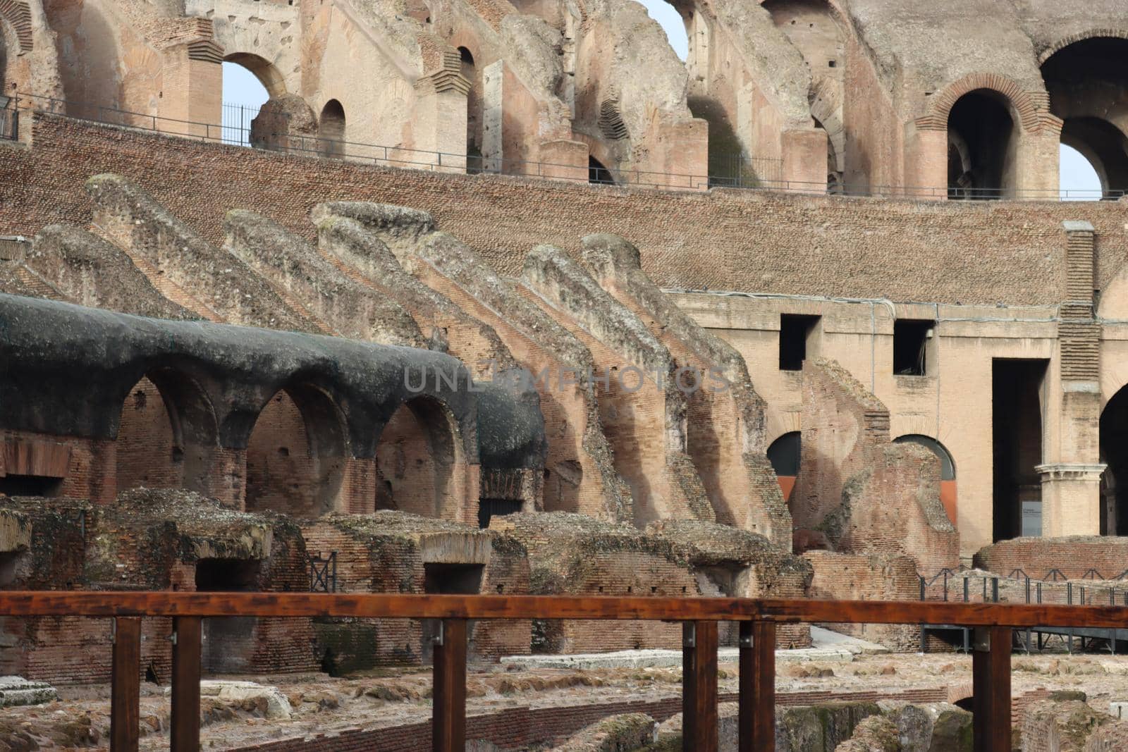 ROME, ITALY - February 05, 2022: Panoramic view around the Colosseum in city of Rome, Italy. Cold and gray sky in the background. Macro photography of the green parks with the old buildings.