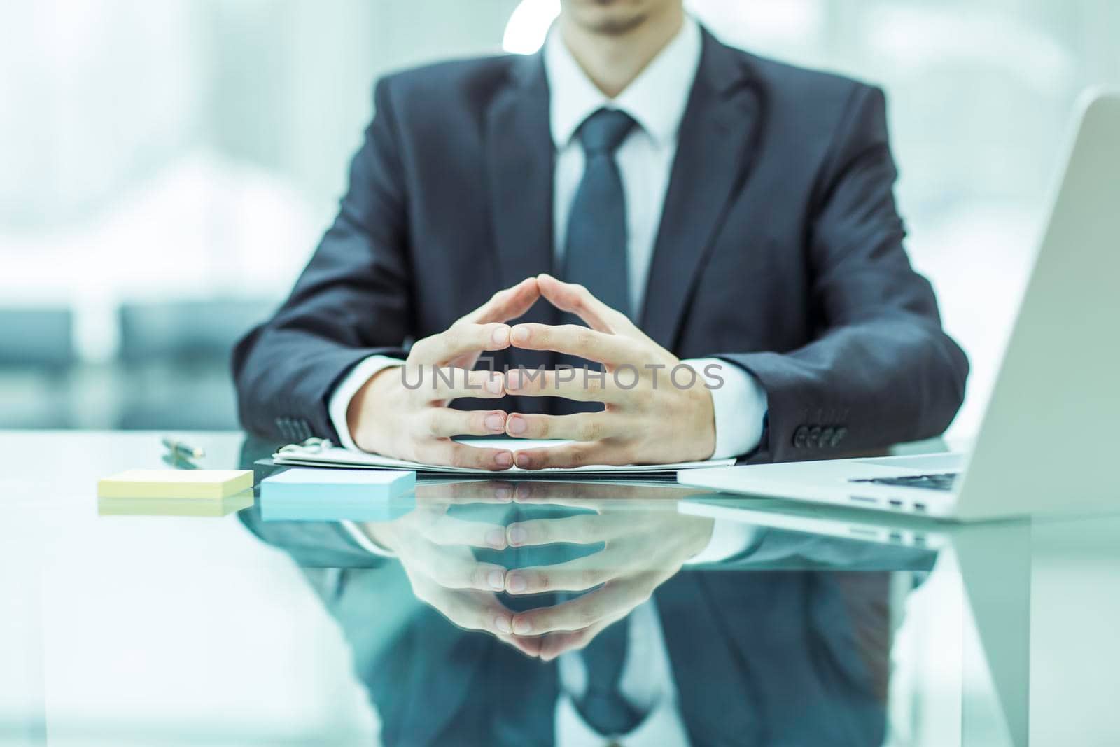close-up of a successful businessman sitting behind a Desk, hands folded in front of him
