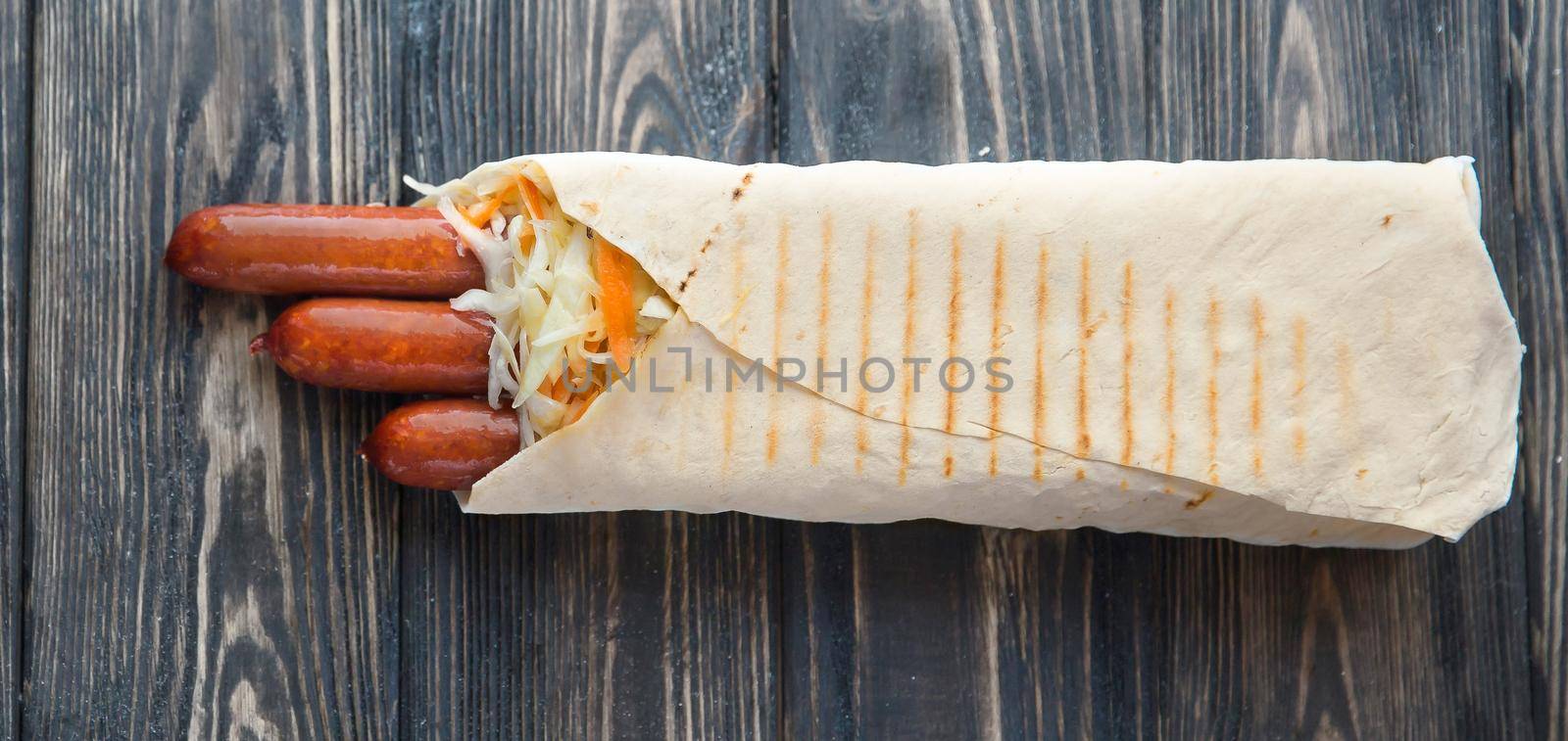 smoked sausage in pita bread on a dark wooden background.photo with copy space.