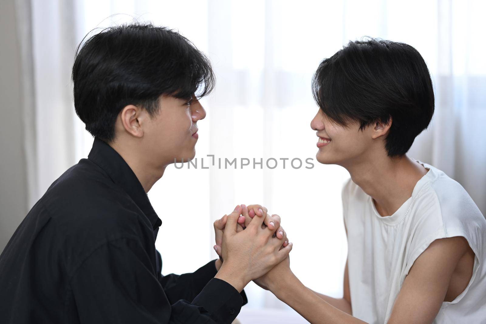 Loving same sex male couple holding hands together and being in love. Homosexual relationships and alternative love lifestyle concept by prathanchorruangsak