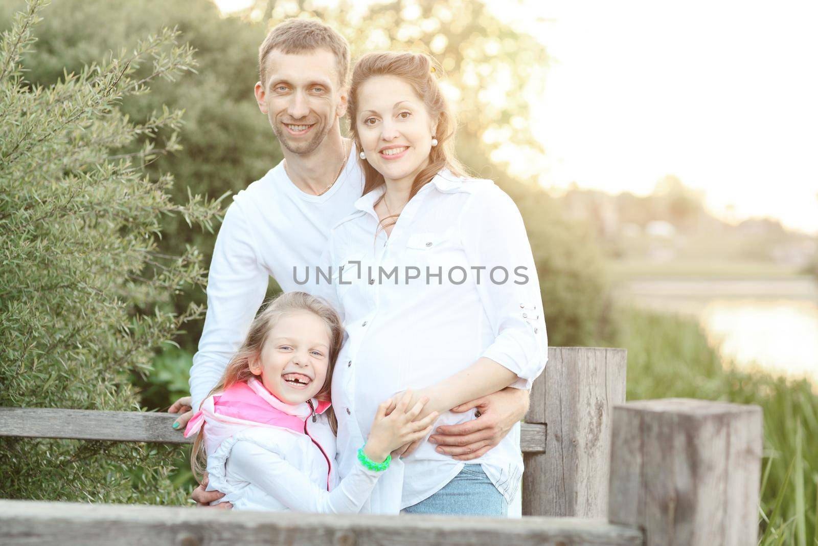 pregnant mom,happy father and little daughter on a walk in the Park on a Sunny day.