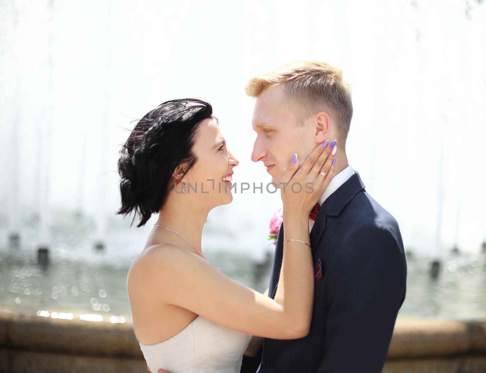 closeup portrait of bride and groom standing next to the fountain by SmartPhotoLab